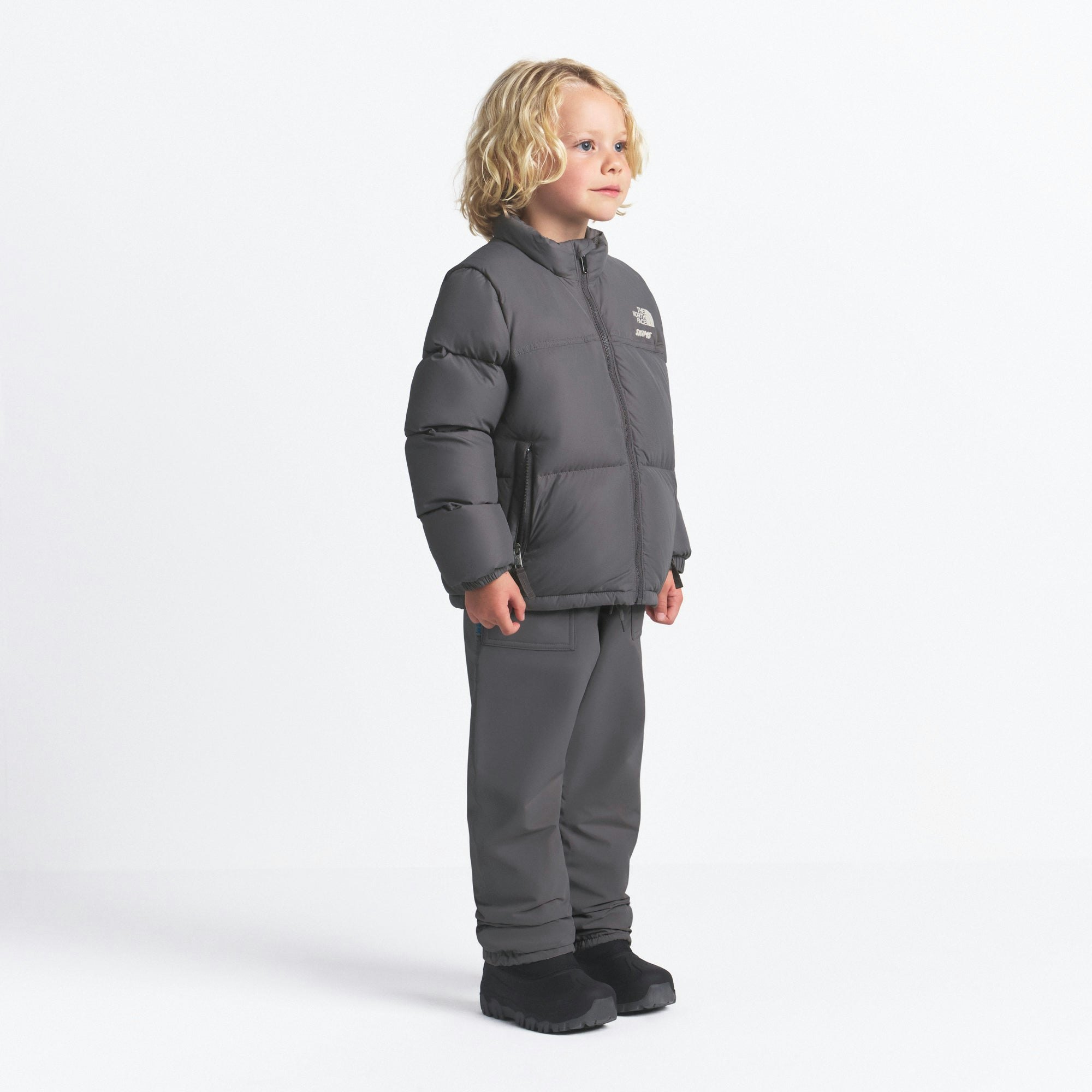 THE NORTH FACE X SKIMS KIDS' 1996 NUPTSE JACKET | GUNMETAL ON A MODEL FRONT VIEW @ | FOCUS: 0.0, 1.0, 0.9