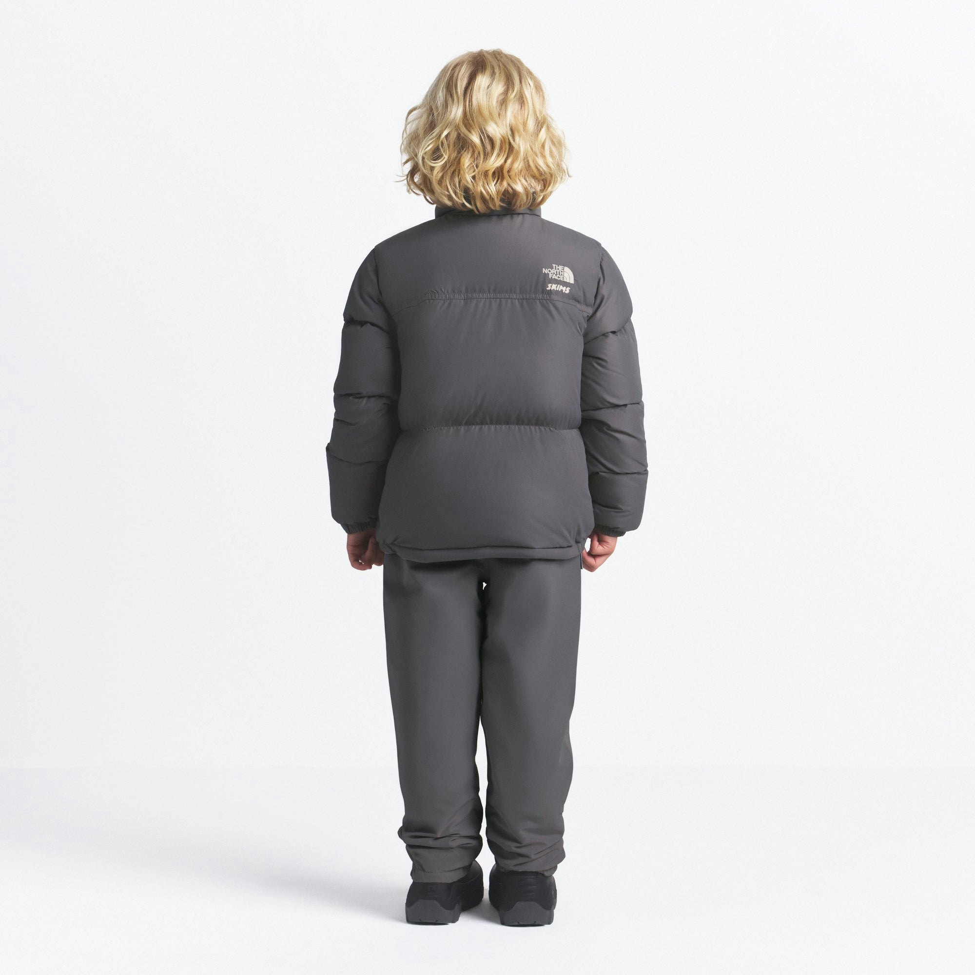 THE NORTH FACE X SKIMS KIDS' 1996 NUPTSE JACKET | GUNMETAL ON A MODEL FRONT VIEW @ | FOCUS: 0.0, 1.0, 0.9