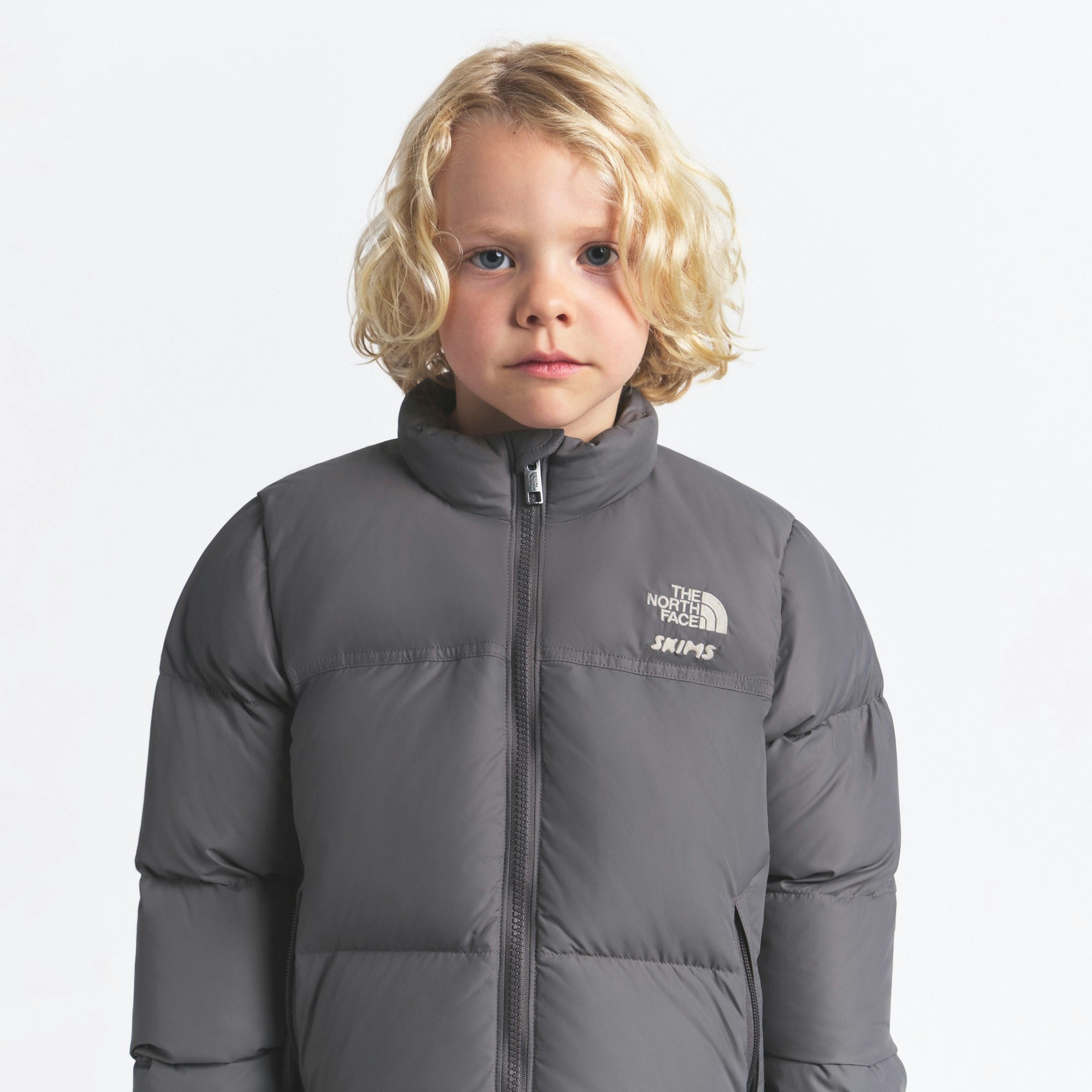 THE NORTH FACE X SKIMS KIDS' 1996 NUPTSE JACKET | GUNMETAL ON A MODEL FRONT VIEW @ | FOCUS: 0.0, 1.0, 0.9