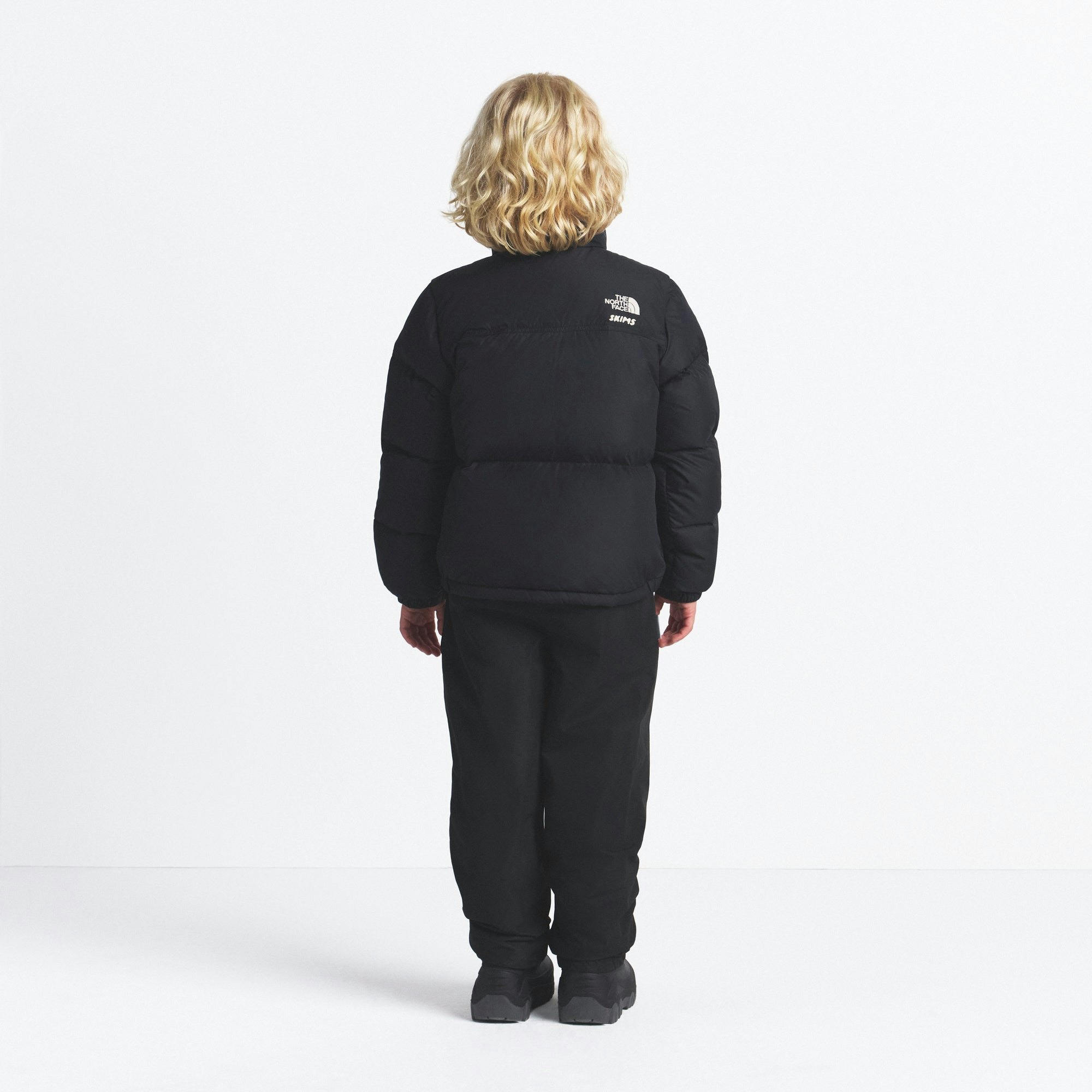 THE NORTH FACE X SKIMS KIDS' 1996 NUPTSE JACKET | ONYX ON A MODEL FRONT VIEW @ | FOCUS: 0.0, 1.0, 0.9