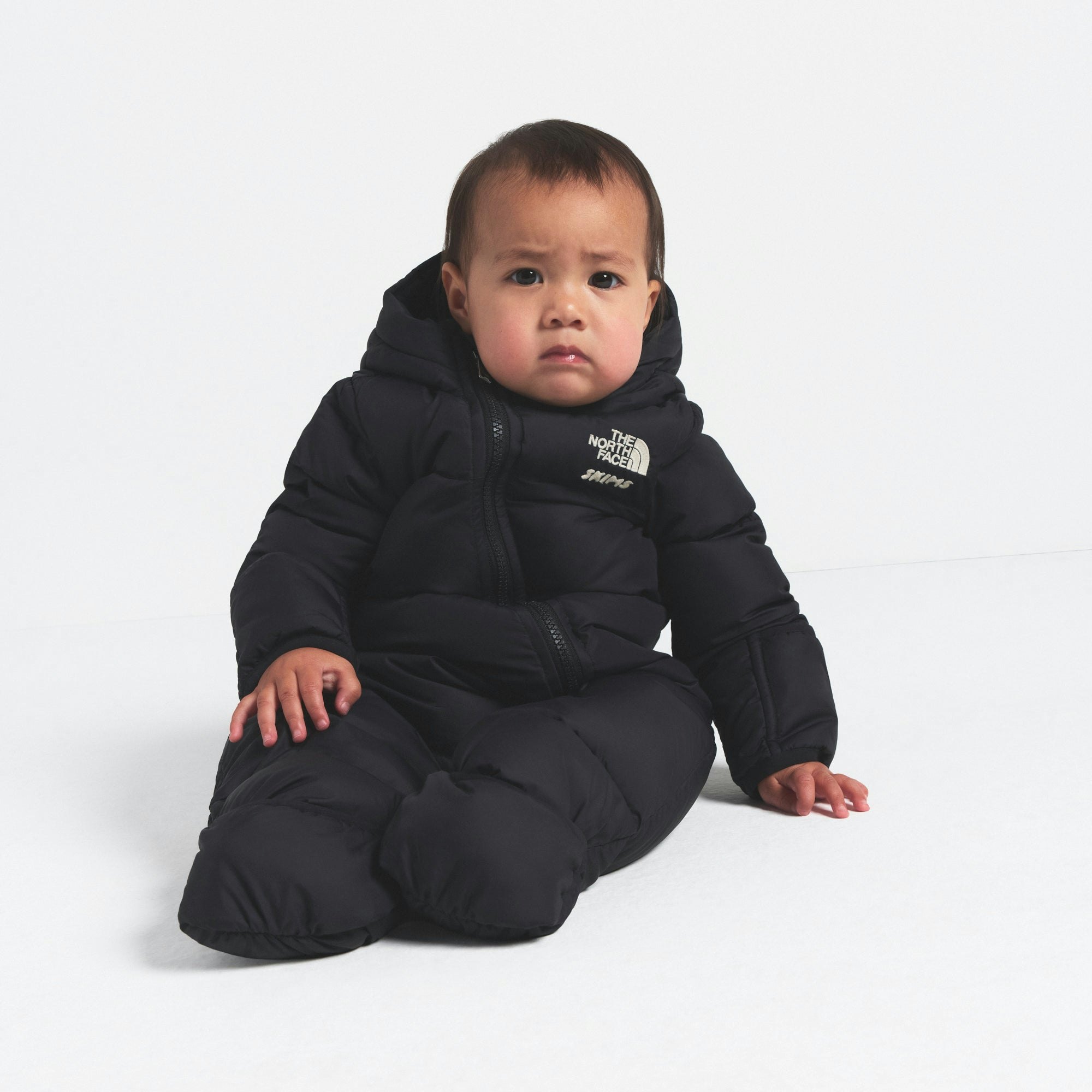 THE NORTH FACE X SKIMS BABY 1996 NUPTSE ONE-PIECE | ONYX ON A MODEL FRONT VIEW @ | FOCUS: 0.0, 1.0, 0.9