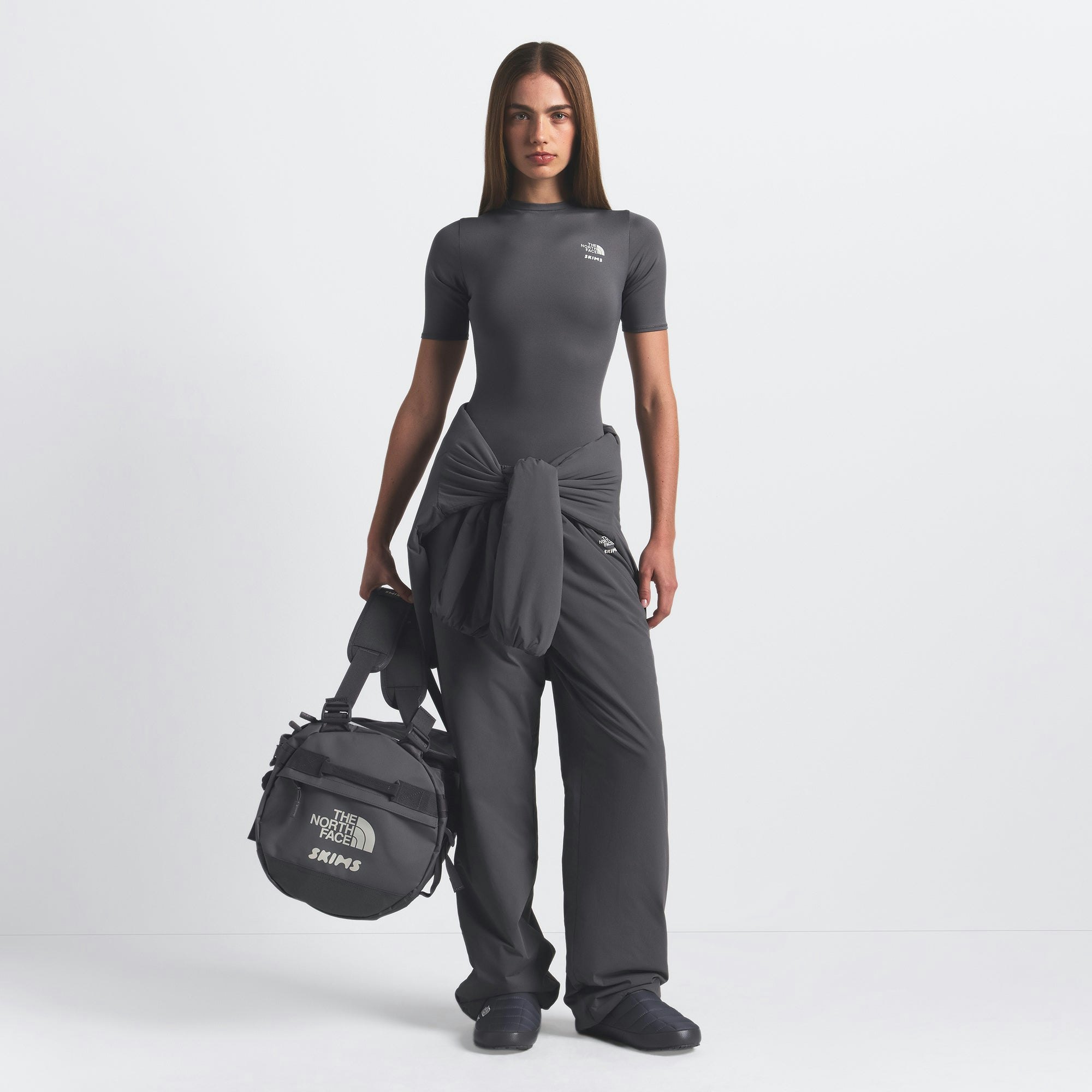 THE NORTH FACE X SKIMS SMALL BASE CAMP DUFFLE BAG | GUNMETAL ON A MODEL FRONT VIEW @ | FOCUS: 0.0, 1.0, 0.9