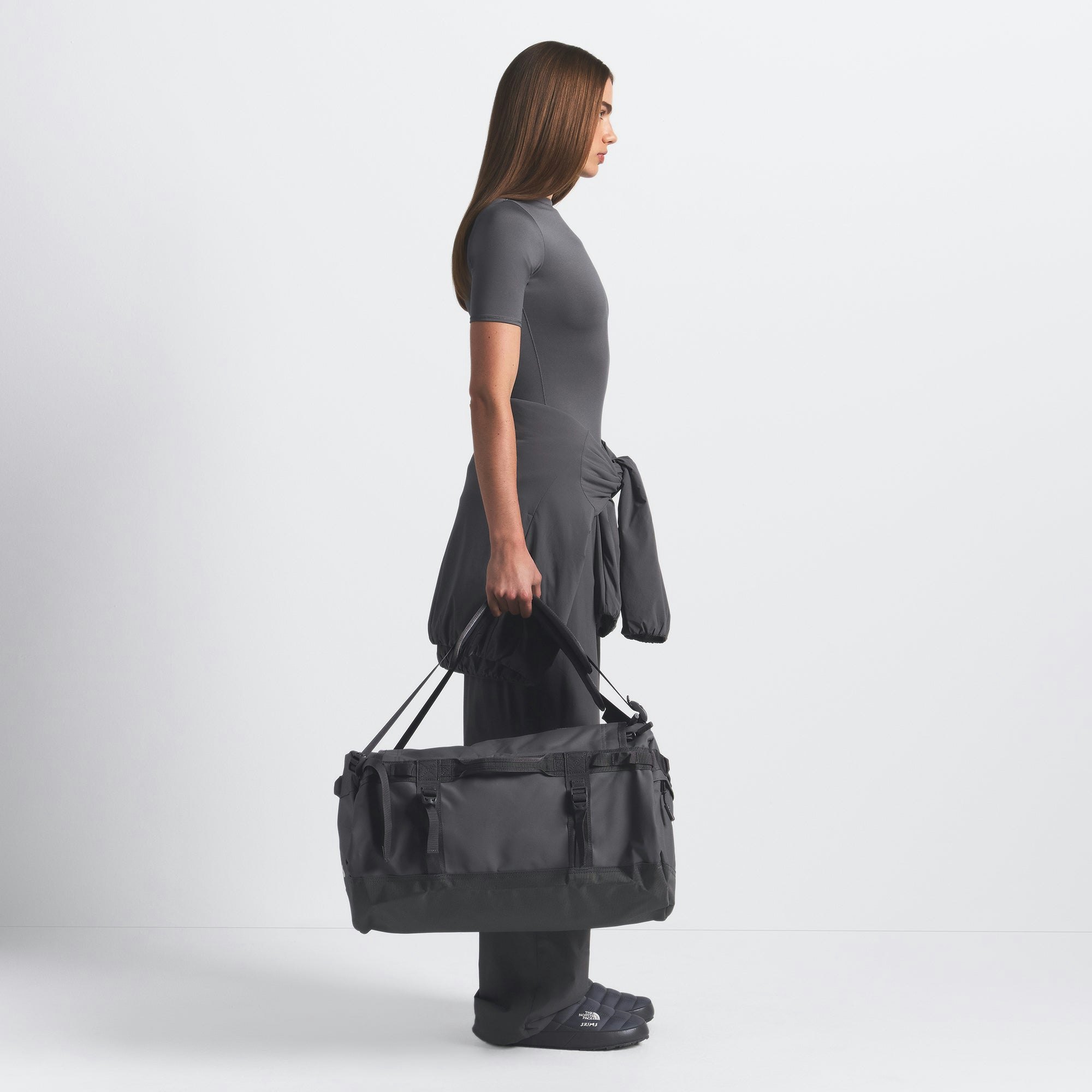 THE NORTH FACE X SKIMS SMALL BASE CAMP DUFFLE BAG | GUNMETAL ON A MODEL FRONT VIEW @ | FOCUS: 0.0, 1.0, 0.9