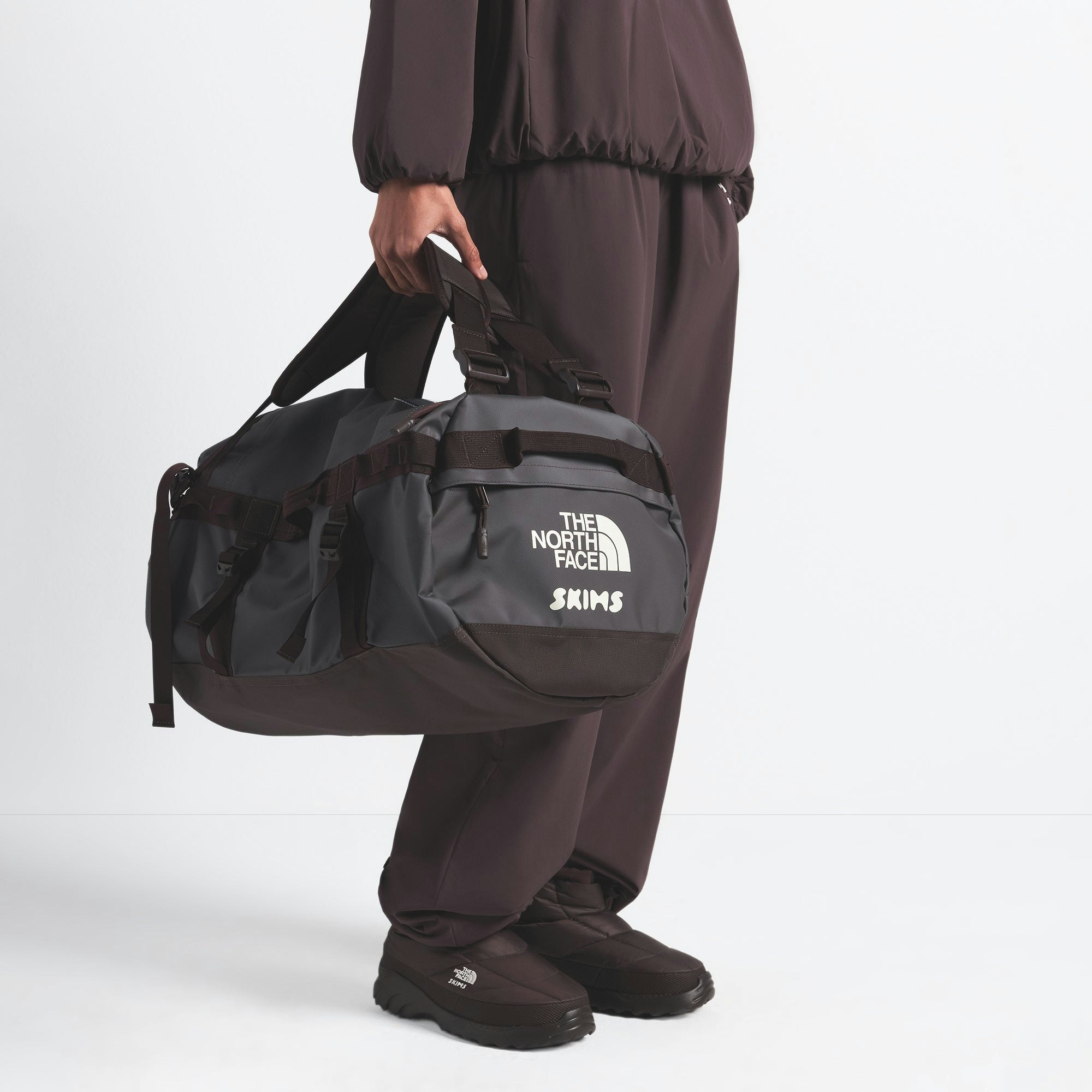THE NORTH FACE X SKIMS SMALL BASE CAMP DUFFLE BAG | PHOENIX ON A MODEL FRONT VIEW @ | FOCUS: 0.0, 1.0, 0.9