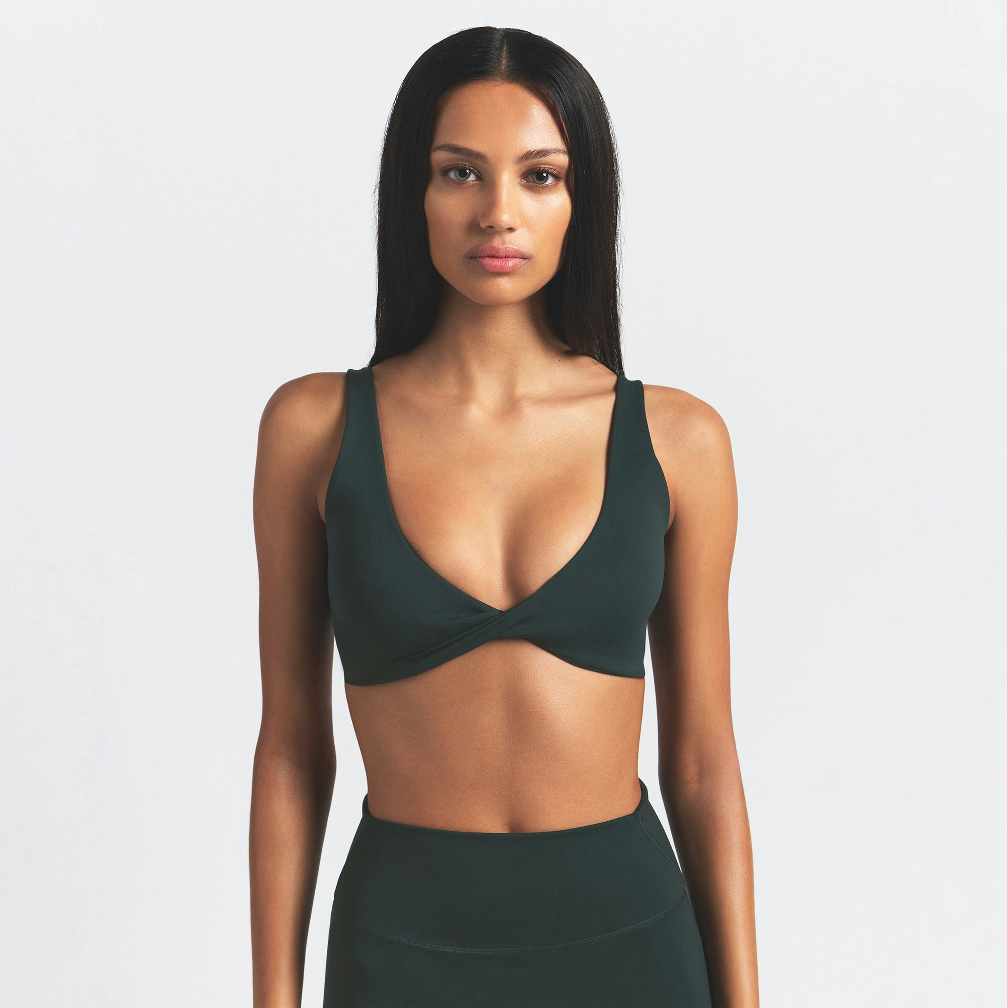 NikeSKIMS MATTE TWIST-FRONT BRA | DARK TEAL ON A MODEL SIDE VIEW @ | FOCUS: 0.0, 1.0, 0.9
