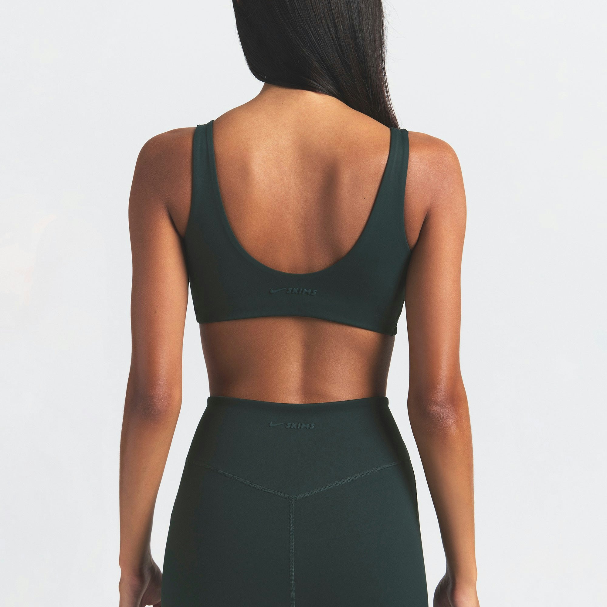 NikeSKIMS MATTE TWIST-FRONT BRA | DARK TEAL ON A MODEL SIDE VIEW @ | FOCUS: 0.0, 1.0, 0.9