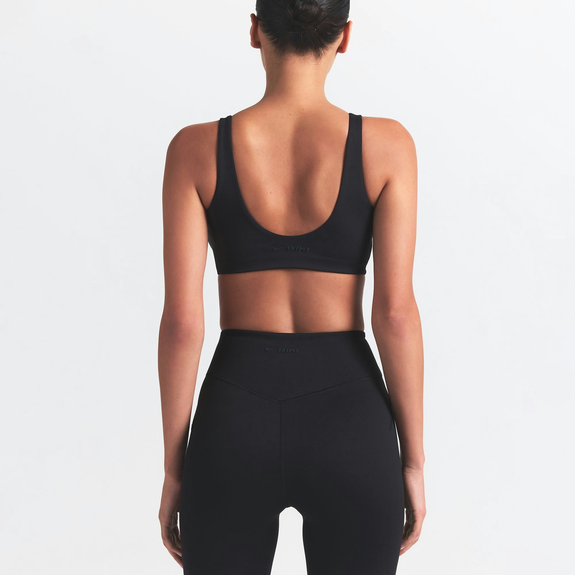 NikeSKIMS MATTE TWIST-FRONT BRA | OBSIDIAN ON A MODEL BACK VIEW @ | FOCUS: 0.0, 1.0, 0.9