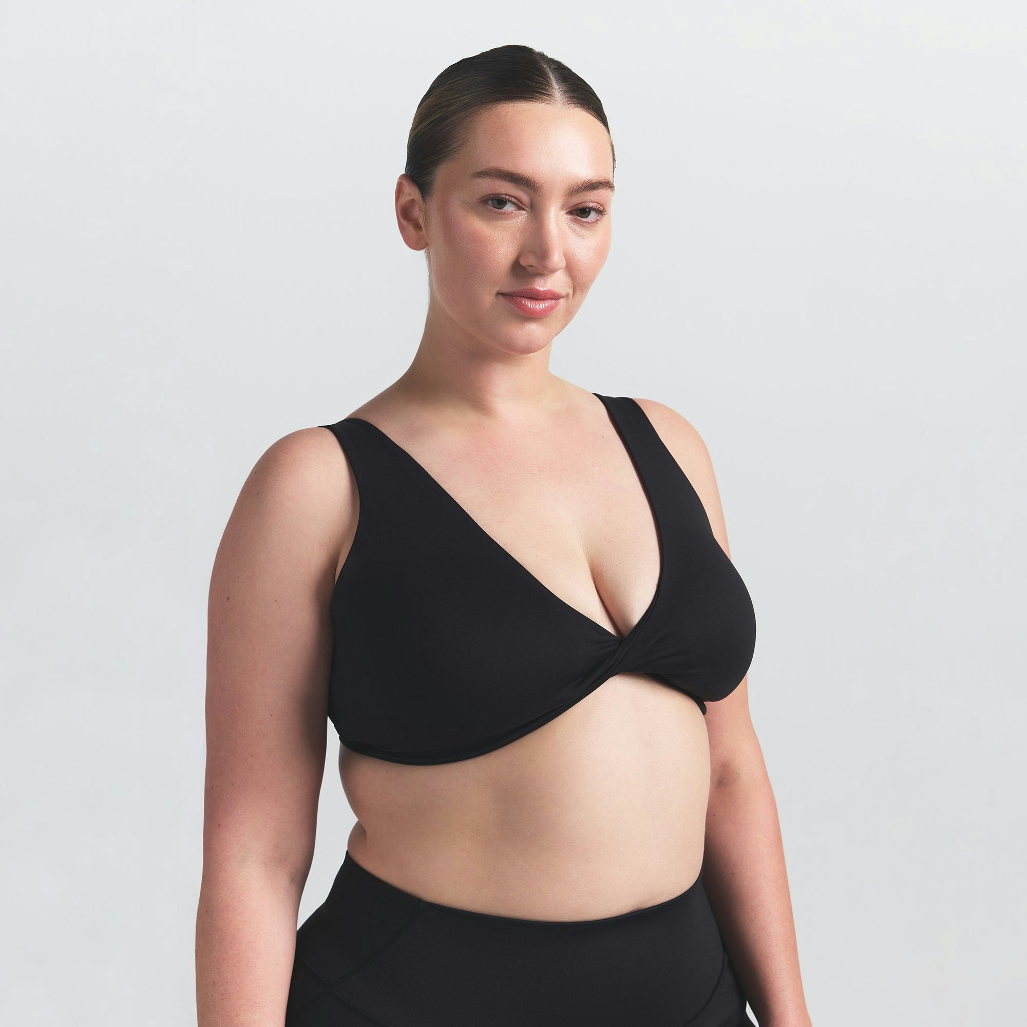 NikeSKIMS MATTE TWIST-FRONT BRA | OBSIDIAN ON A MODEL FRONT VIEW @ | FOCUS: 0.0, 1.0, 0.9