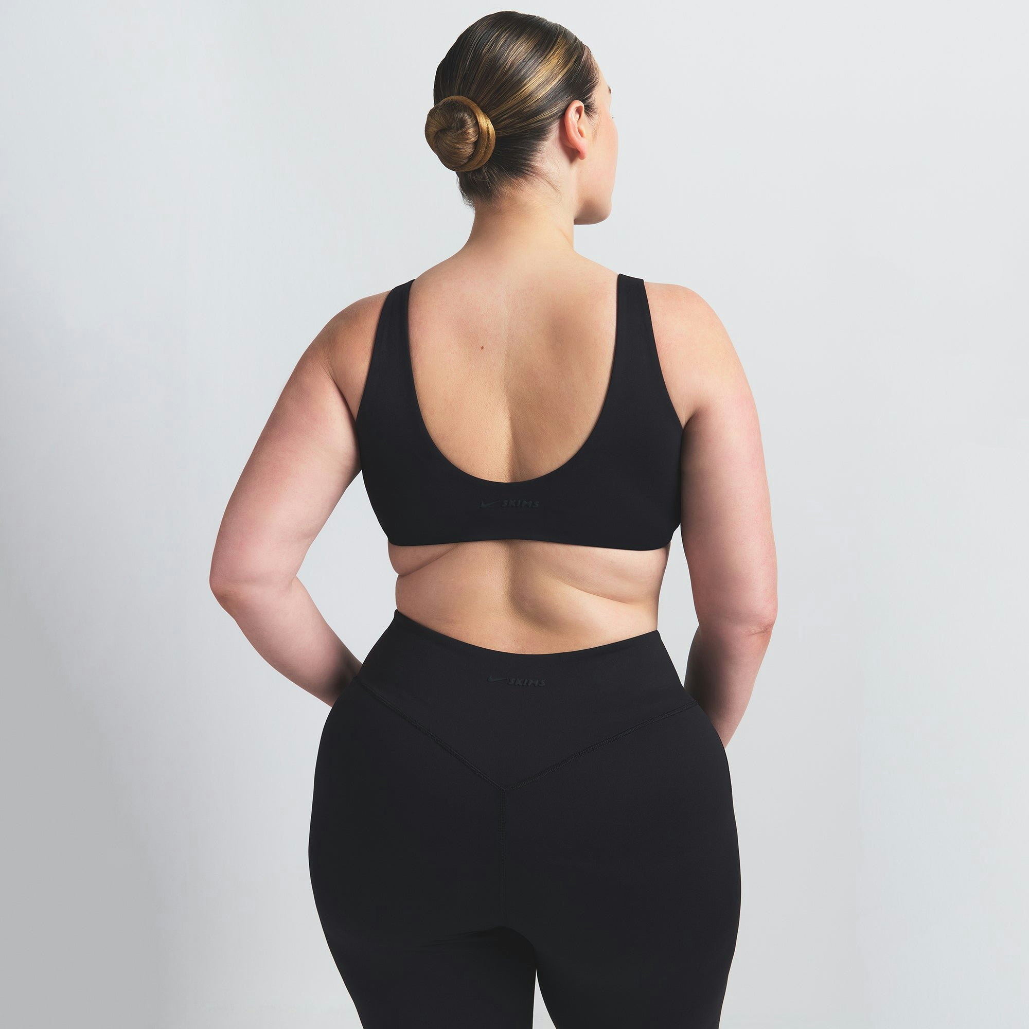 NikeSKIMS MATTE TWIST-FRONT BRA | OBSIDIAN ON A MODEL BACK VIEW @ | FOCUS: 0.0, 1.0, 0.9