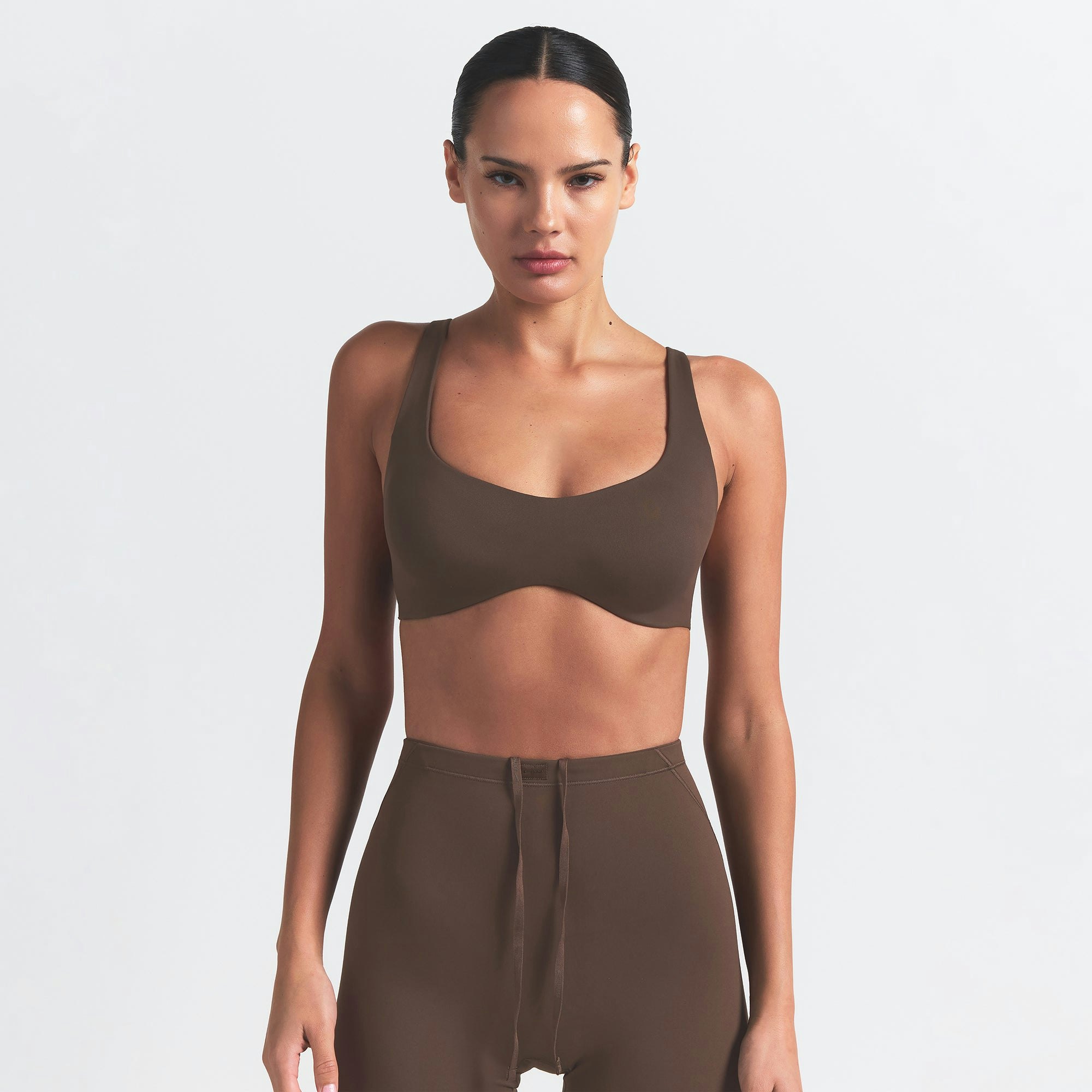 NikeSKIMS MATTE SHAPING SCOOP BRA | DARK SEPIA ON A MODEL FRONT VIEW @ | FOCUS: 0.0, 1.0, 0.9