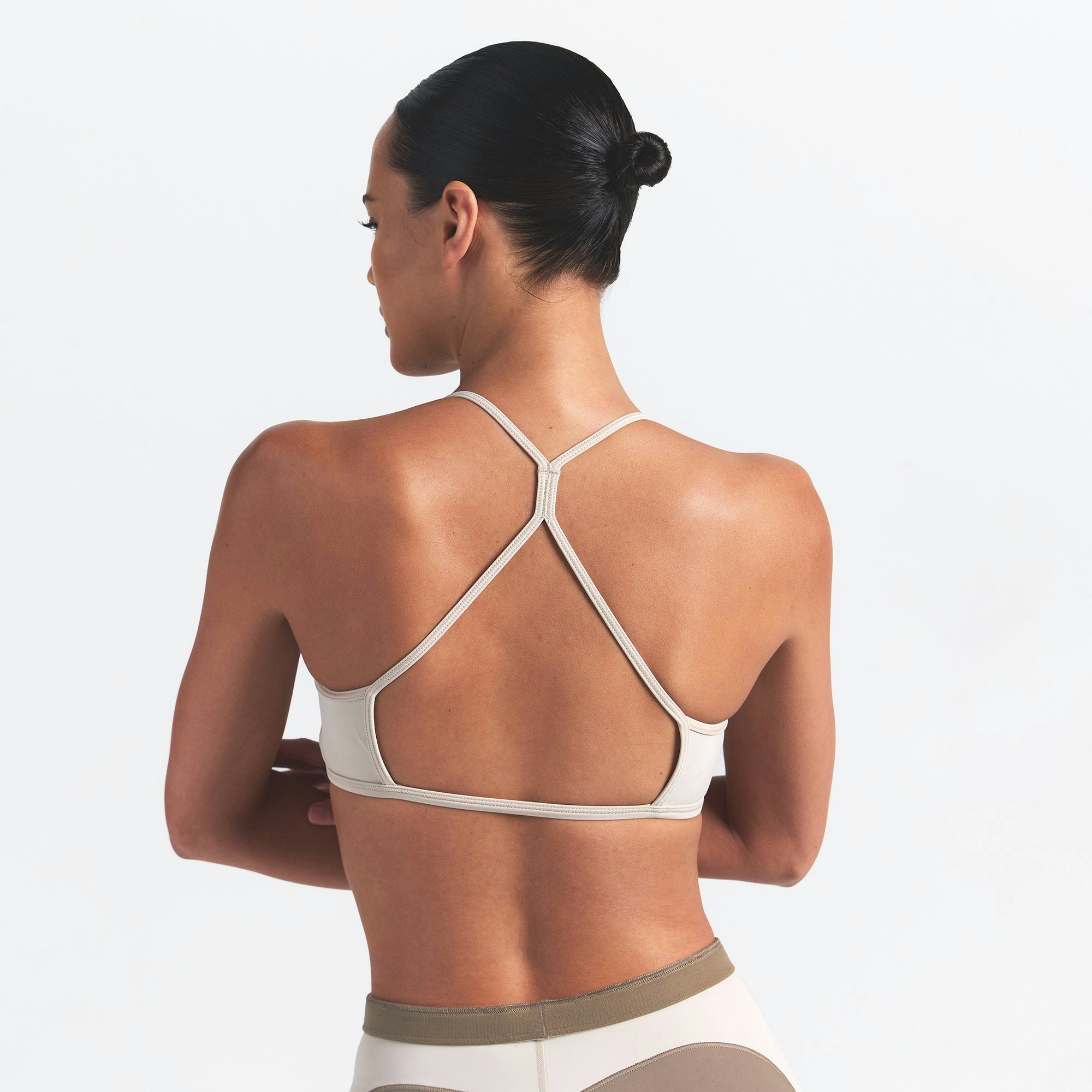NikeSKIMS SHINE MICRO SCOOP BRA | TRUFFLE AND STONE ON A MODEL BACK VIEW @ | FOCUS: 0.0, 1.0, 0.9