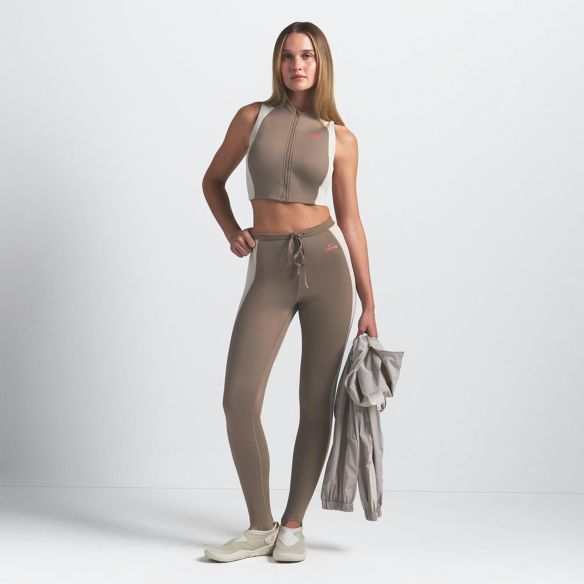 NikeSKIMS SHINE FRONT ZIP BRA | TRUFFLE AND STONE ON A MODEL FRONT VIEW @ | FOCUS: 0.0, 1.0, 0.9