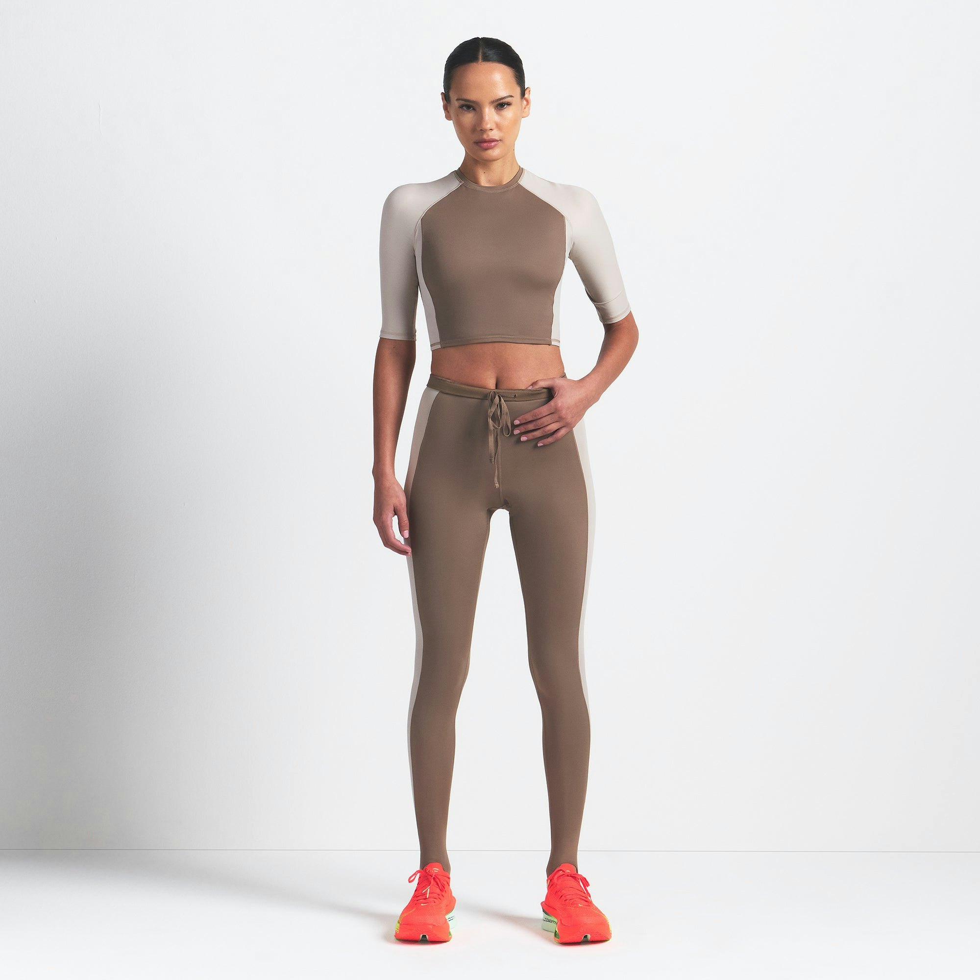 NikeSKIMS SHINE PADDED HALF SLEEVE CROP TOP | TRUFFLE AND STONE ON A MODEL FRONT VIEW @ | FOCUS: 0.0, 1.0, 0.9