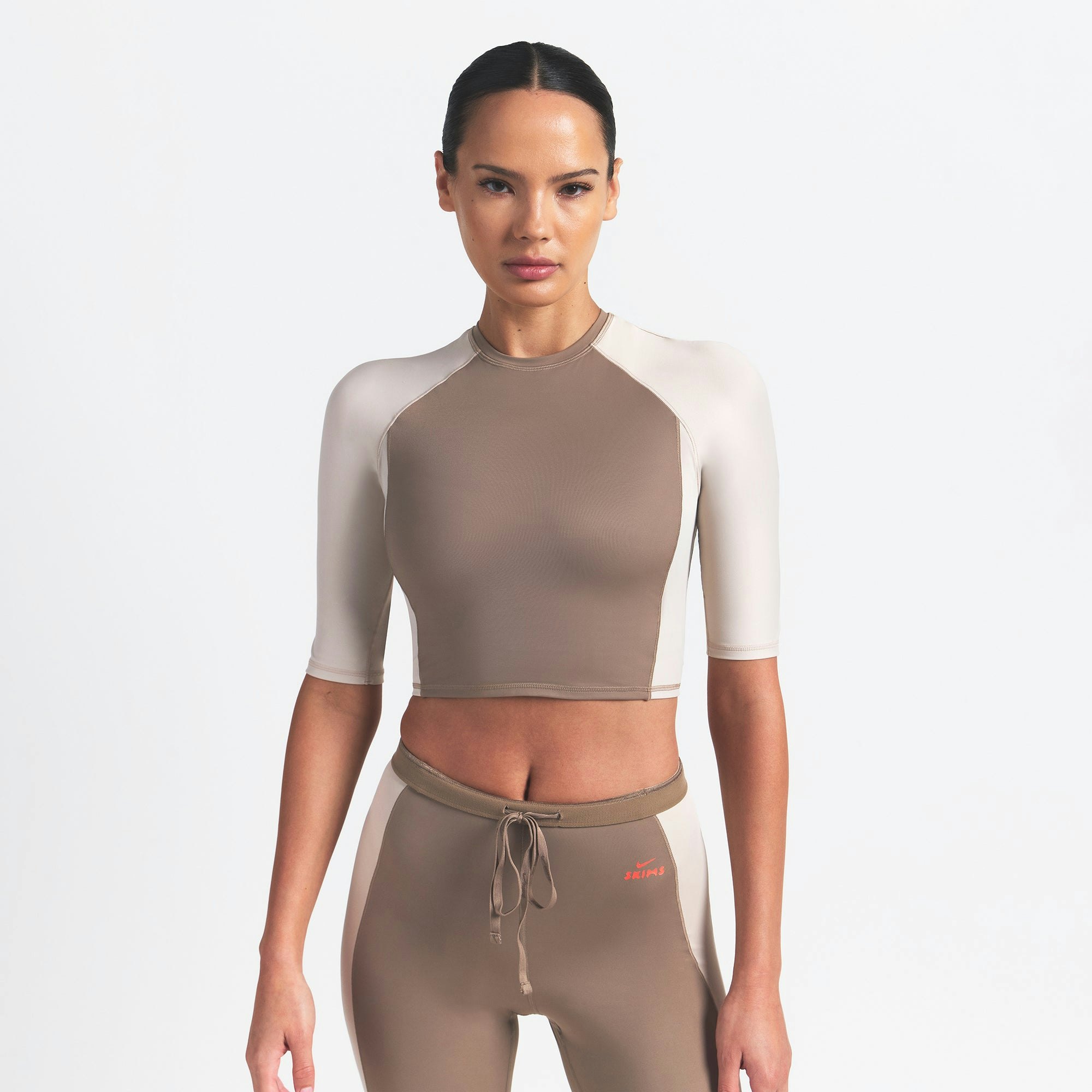 NikeSKIMS SHINE PADDED HALF SLEEVE CROP TOP | TRUFFLE AND STONE ON A MODEL FRONT VIEW @ | FOCUS: 0.0, 1.0, 0.9