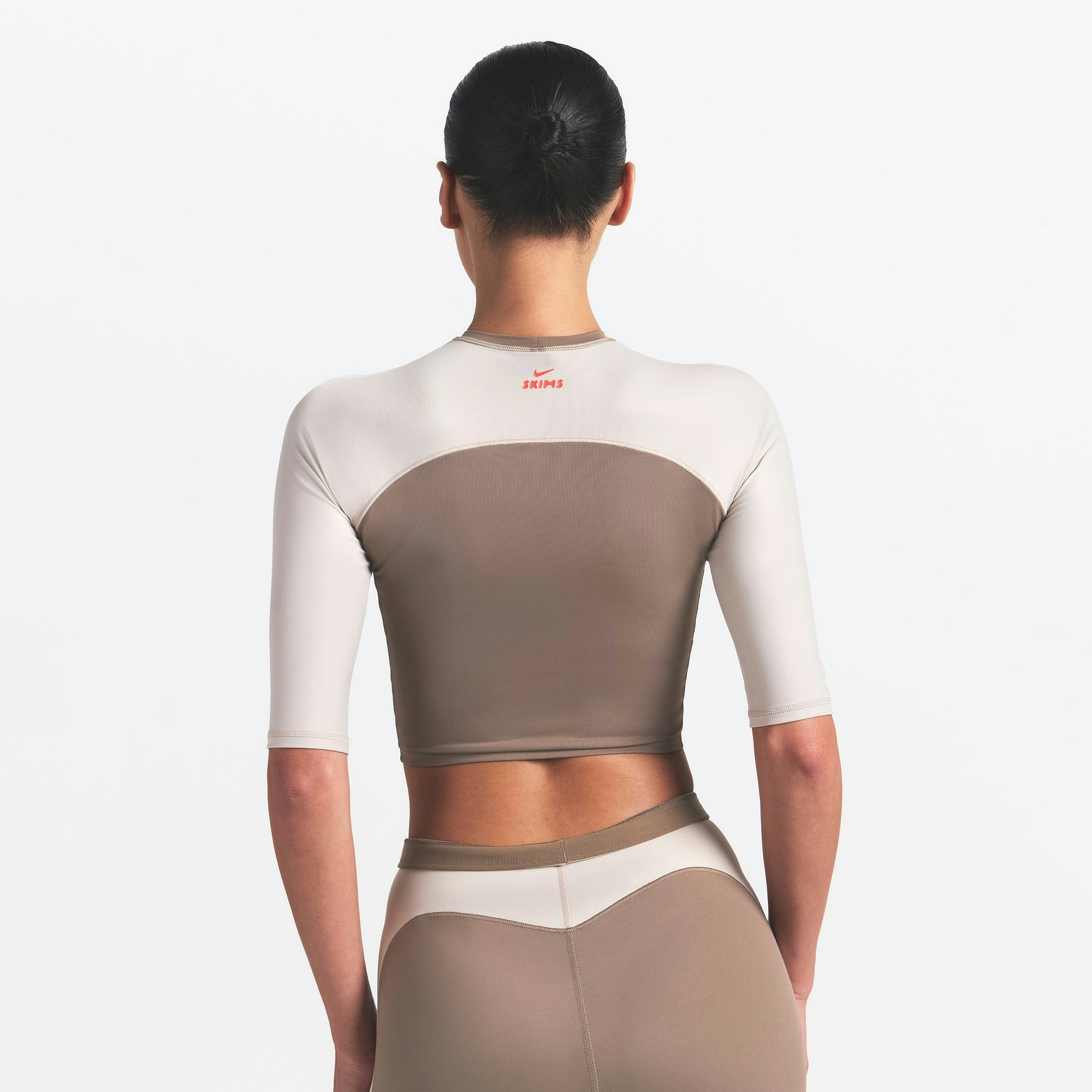 NikeSKIMS SHINE PADDED HALF SLEEVE CROP TOP | TRUFFLE AND STONE ON A MODEL BACK VIEW @ | FOCUS: 0.0, 1.0, 0.9