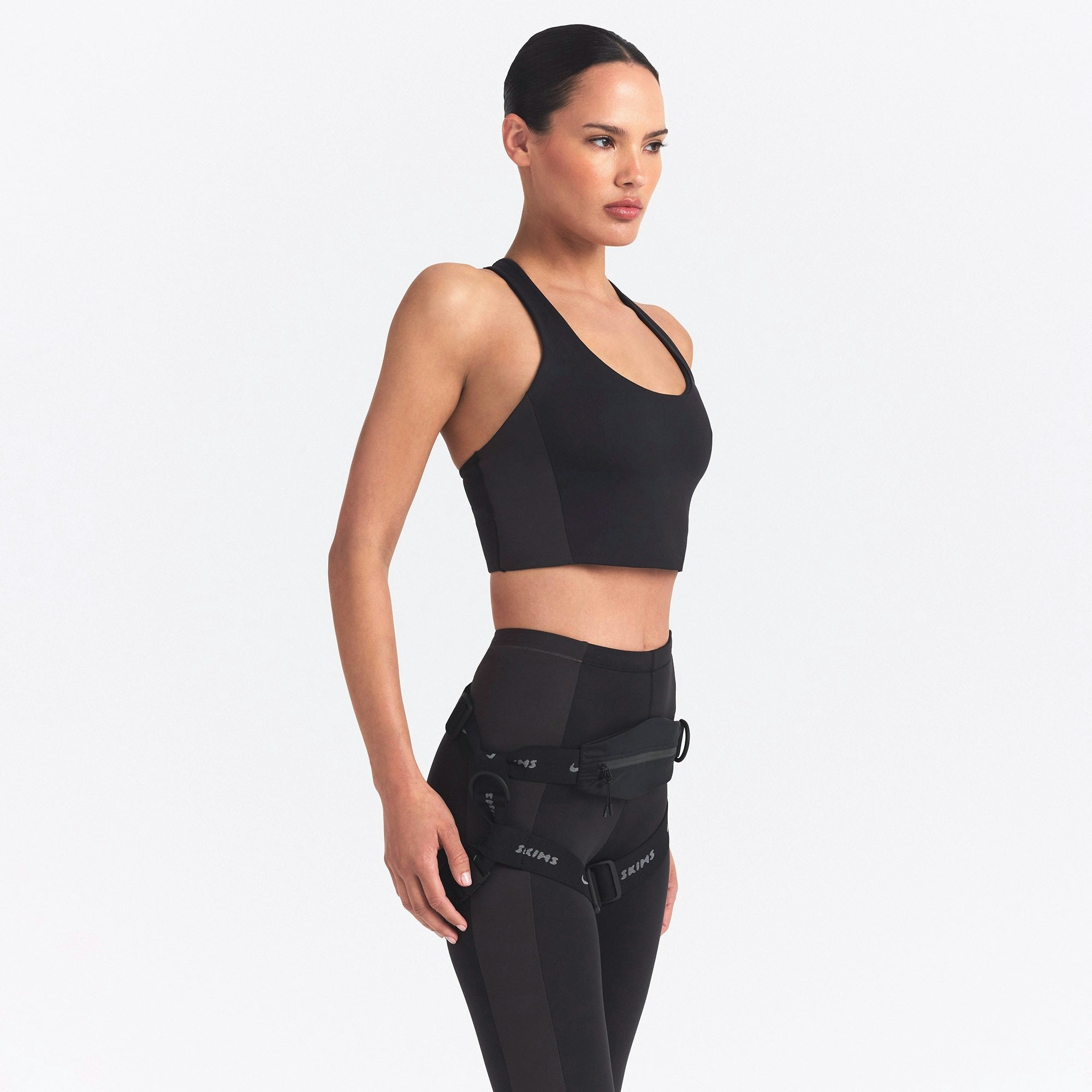 NikeSKIMS MATTE AND SHINE RACERBACK LONGLINE BRA | OBSIDIAN/IGNEOUS ON A MODEL SIDE VIEW @ | FOCUS: 0.0, 1.0, 0.9