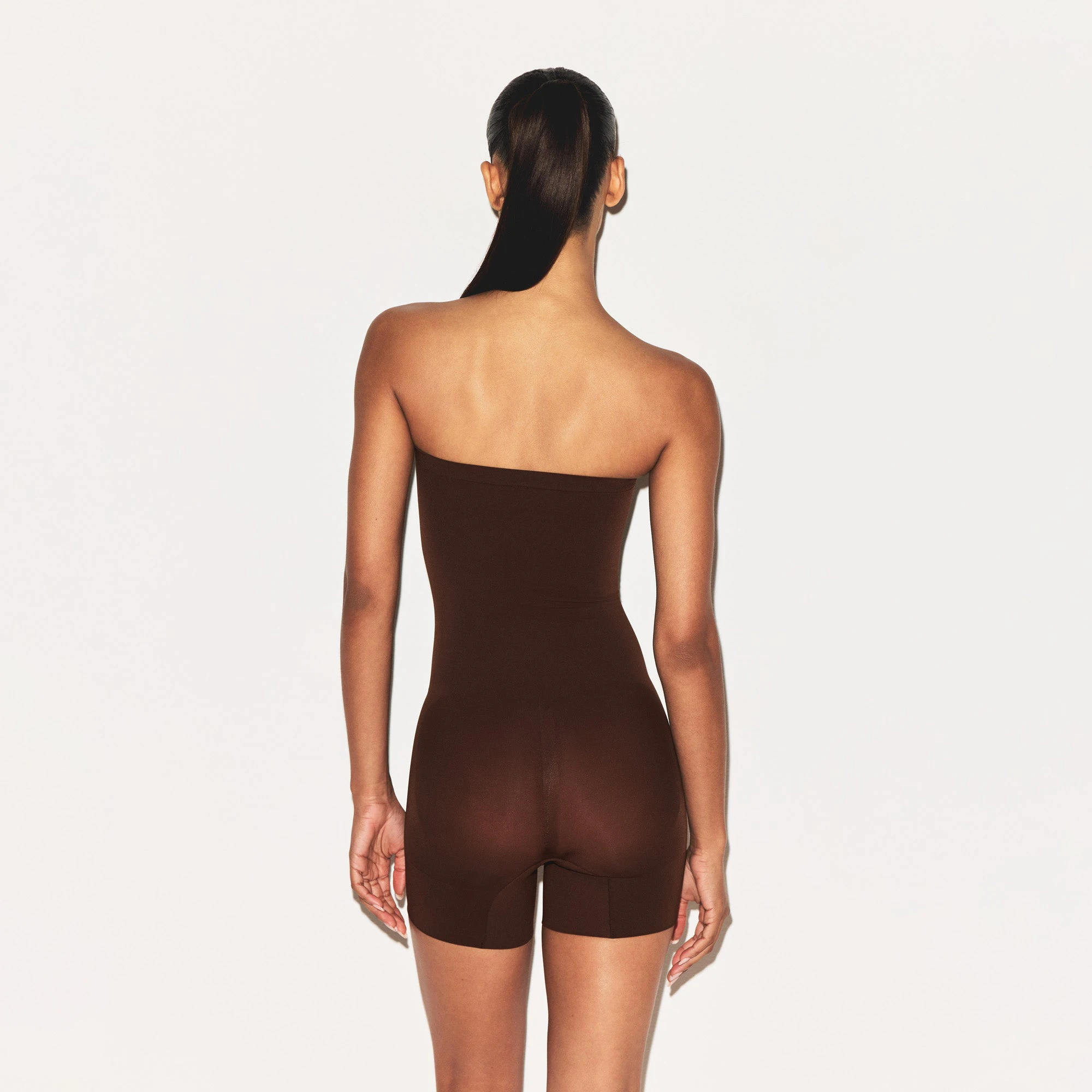 SHEER SEAMLESS STRAPLESS SHORTIE BODYSUIT | COCOA ON A MODEL FRONT VIEW | FOCUS: 0.9, 0.1, 0.7