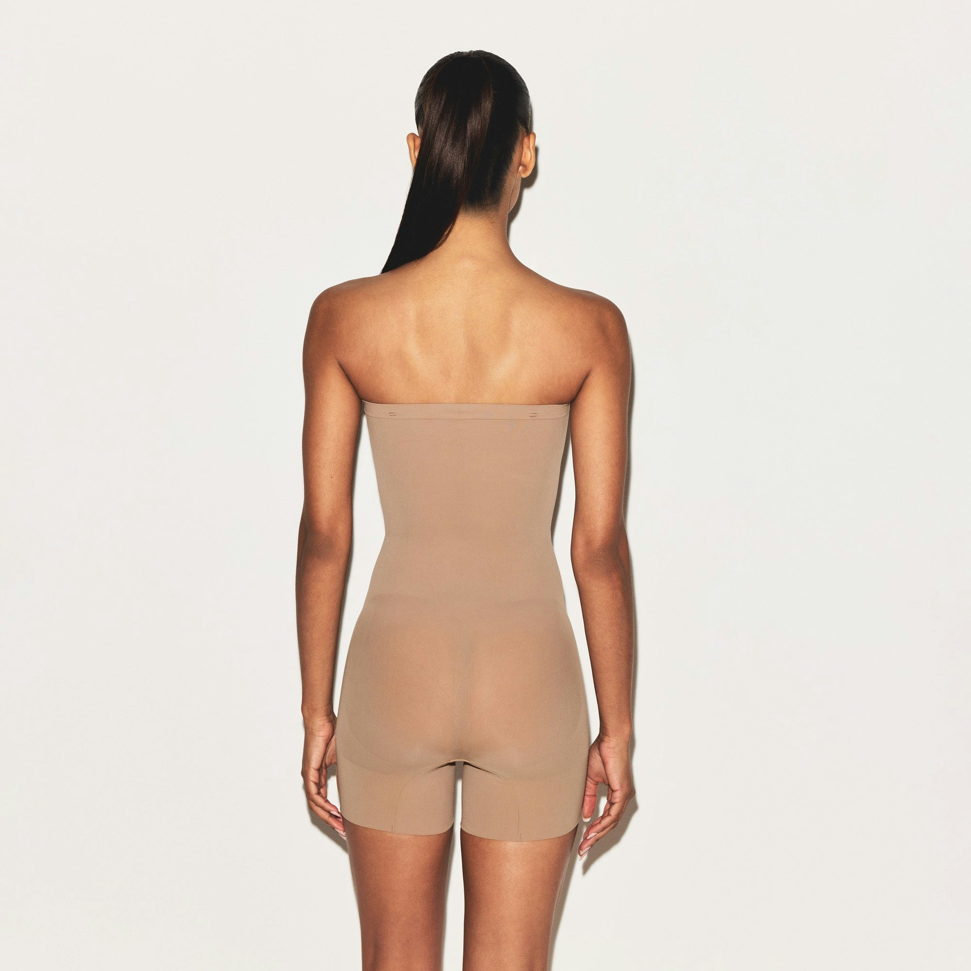 SHEER SEAMLESS STRAPLESS SHORTIE BODYSUIT | SIENNA ON A MODEL FRONT VIEW | FOCUS: 0.9, 0.1, 0.7