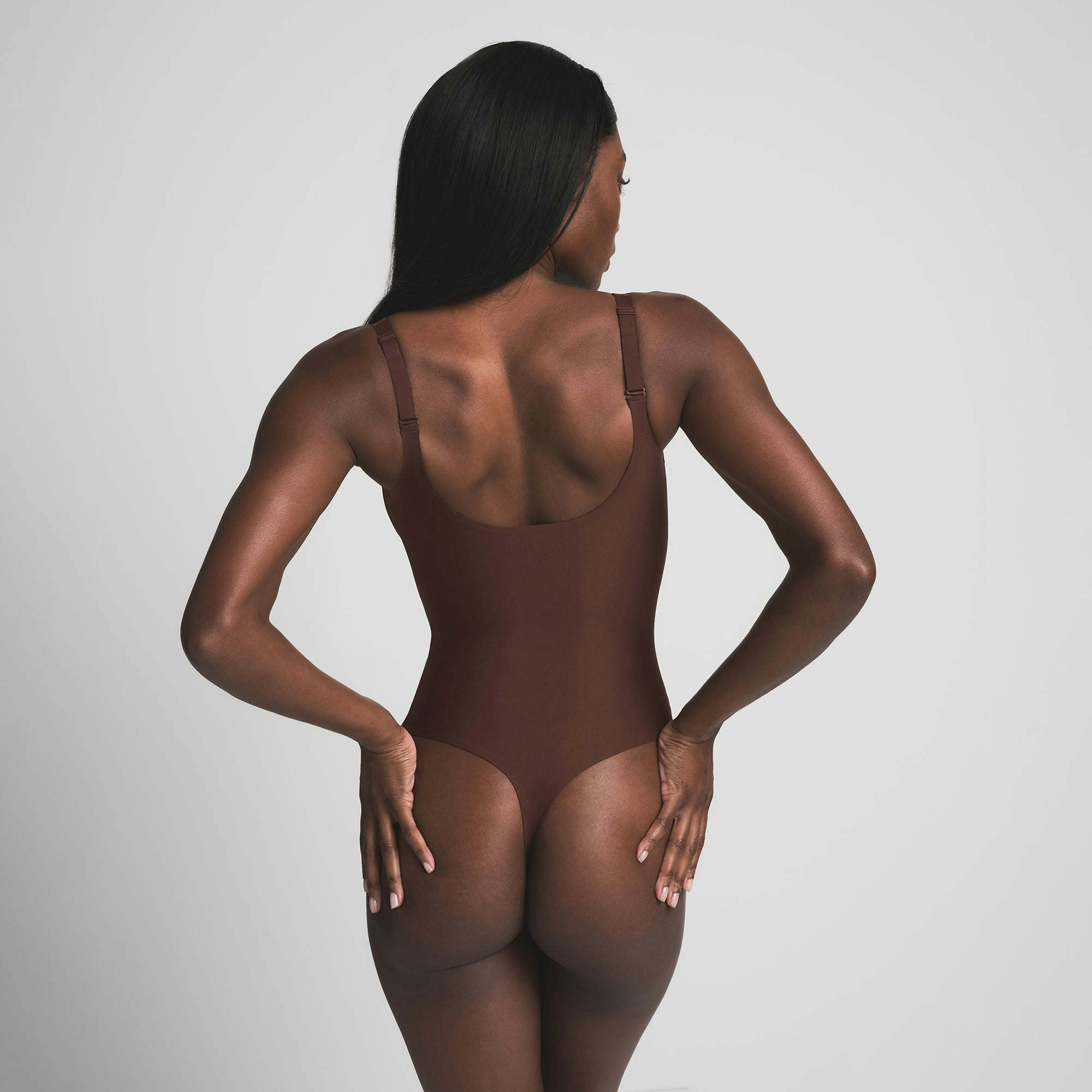 SKIMS BODY UNLINED PLUNGE THONG BODYSUIT | COCOA ON A MODEL BACK VIEW | FOCUS: 0.0, 1.0, 0.9