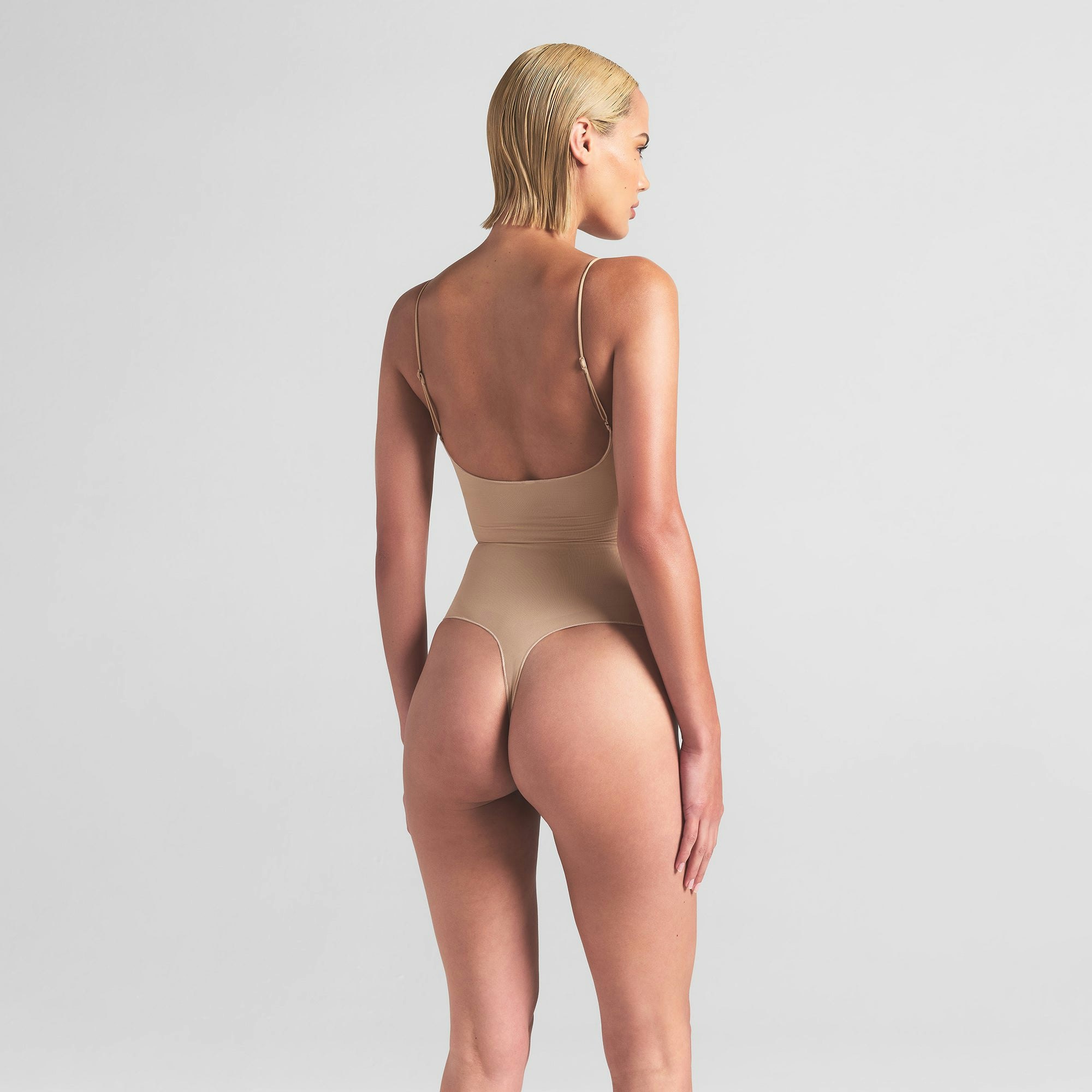 SHEER SEAMLESS THONG BODYSUIT | SAND ON A MODEL BACK VIEW | FOCUS: 0.0, 1.0, 0.9