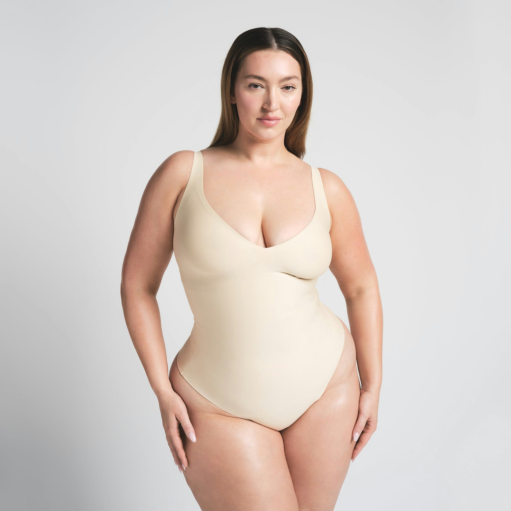 SKIMS BODY UNLINED PLUNGE THONG BODYSUIT | SAND ON A MODEL FRONT VIEW @ | FOCUS: 0.0, 1.0, 0.9