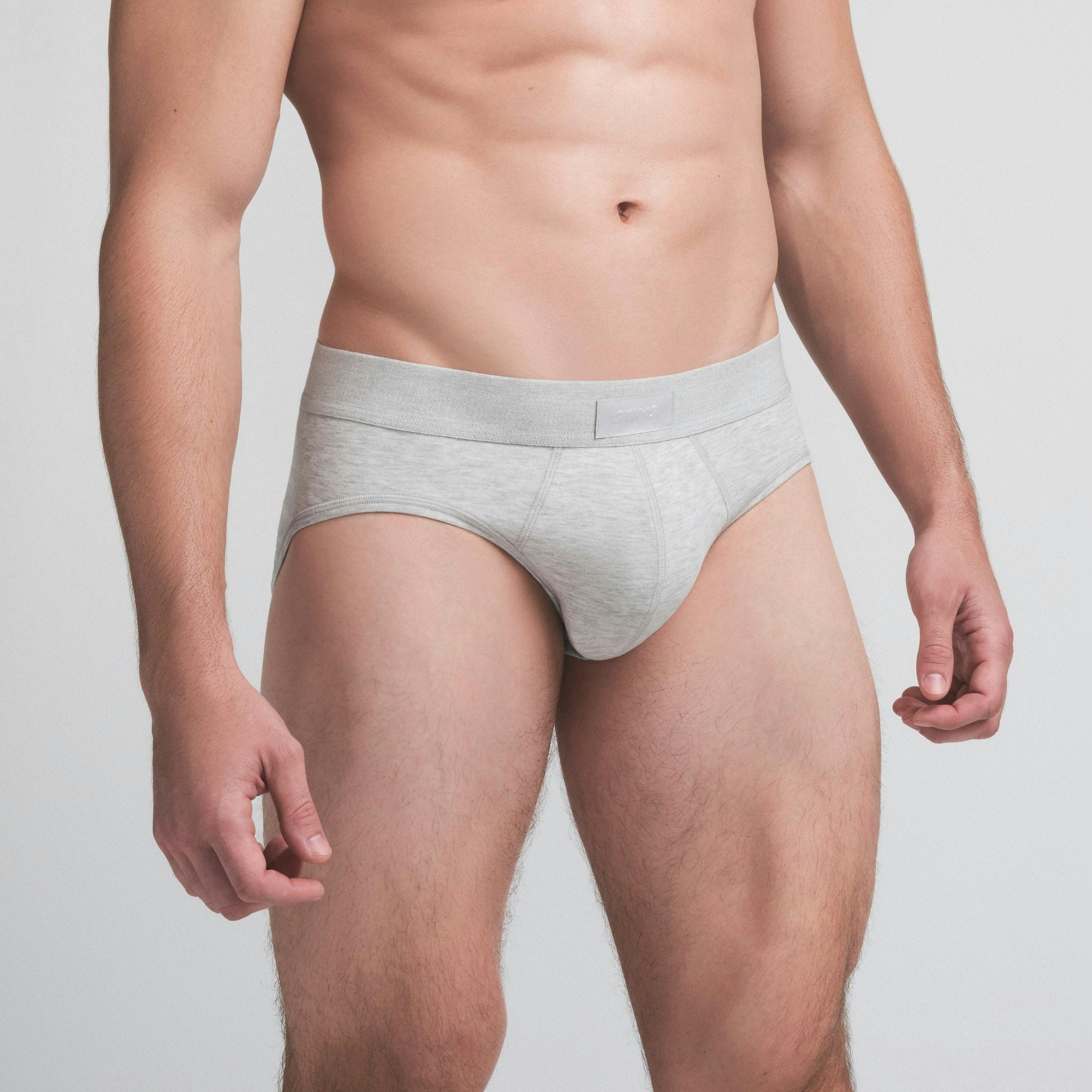 SKIMS COTTON MENS BRIEF | LIGHT HEATHER GREY ON A MODEL SIDE VIEW @ | FOCUS: 0.9, 0.1, 0.7