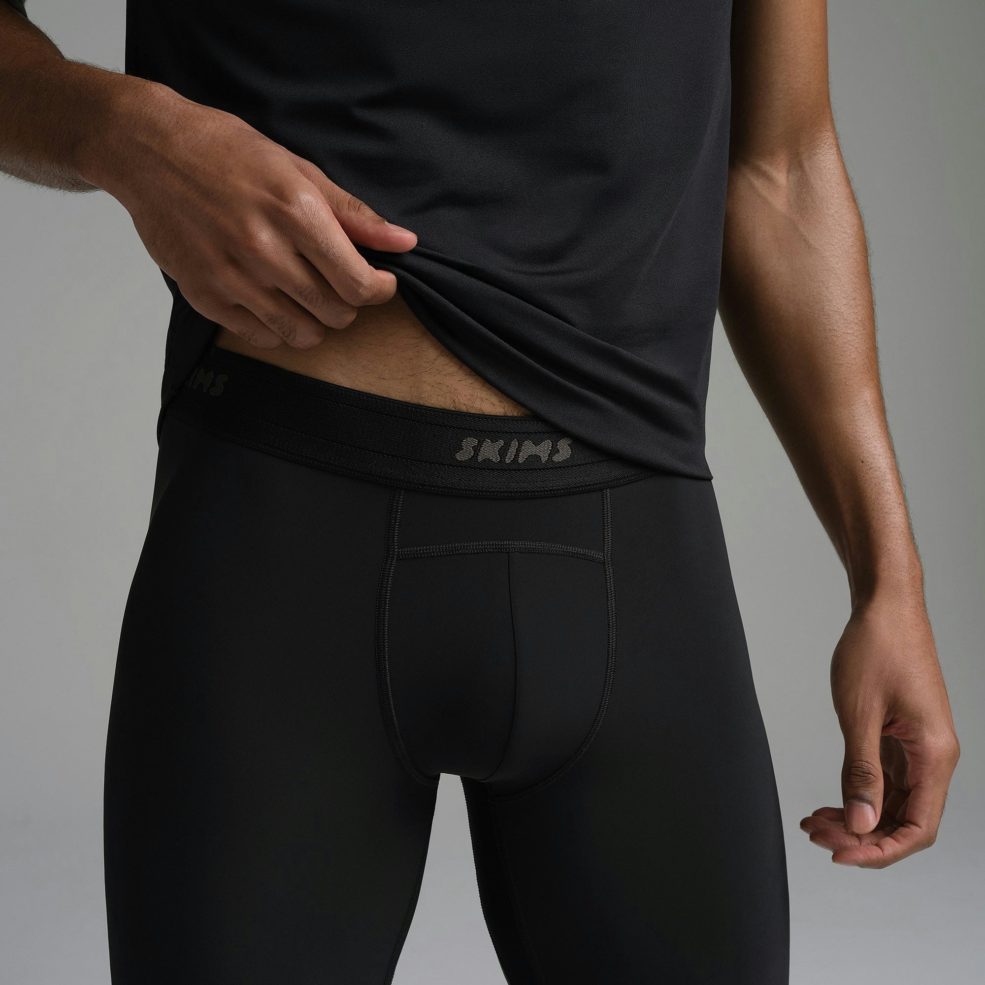SKIMS SPORT MENS LEGGING | OBSIDIAN ON A MODEL SIDE VIEW | FOCUS: 0.0, 1.0, 0.9