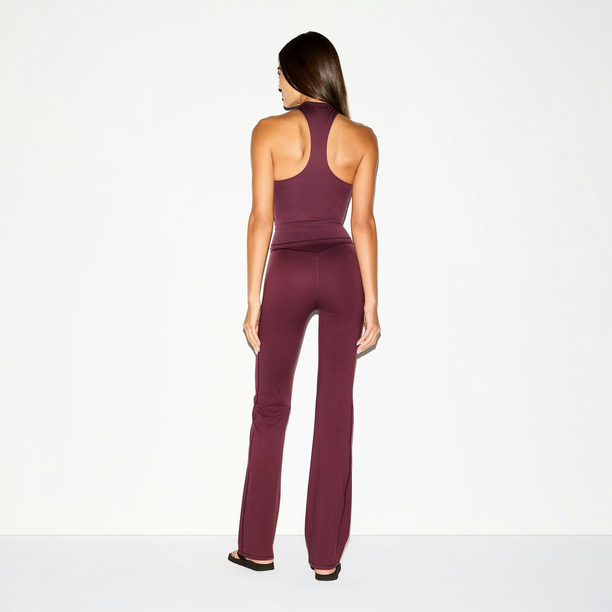 NikeSKIMS MATTE SLIM FLARE LEGGING | CURRANT ON A MODEL BACK VIEW @ | FOCUS: 0.0, 1.0, 0.9