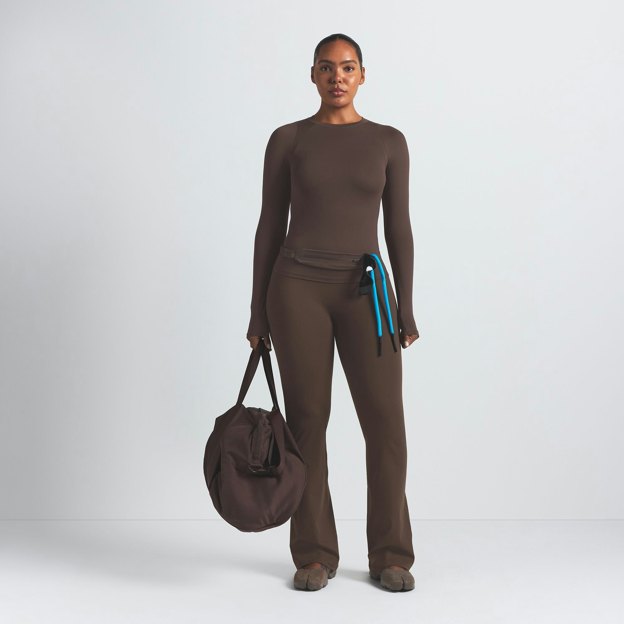 NikeSKIMS MATTE SLIM FLARE LEGGING | DARK SEPIA ON A MODEL FRONT VIEW @ | FOCUS: 0.9, 0.1, 0.7