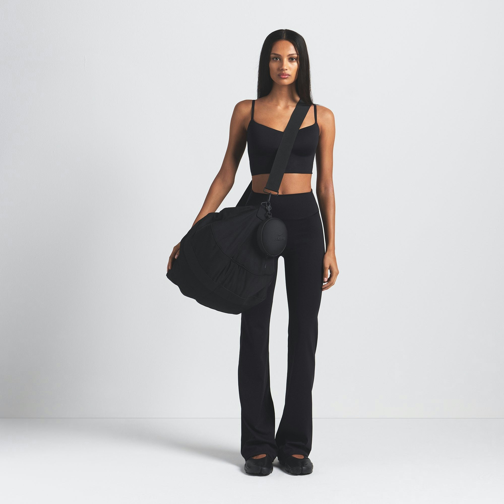 NikeSKIMS MATTE SLIM FLARE LEGGING | OBSIDIAN ON A MODEL FRONT VIEW @ | FOCUS: 0.9, 0.1, 0.7