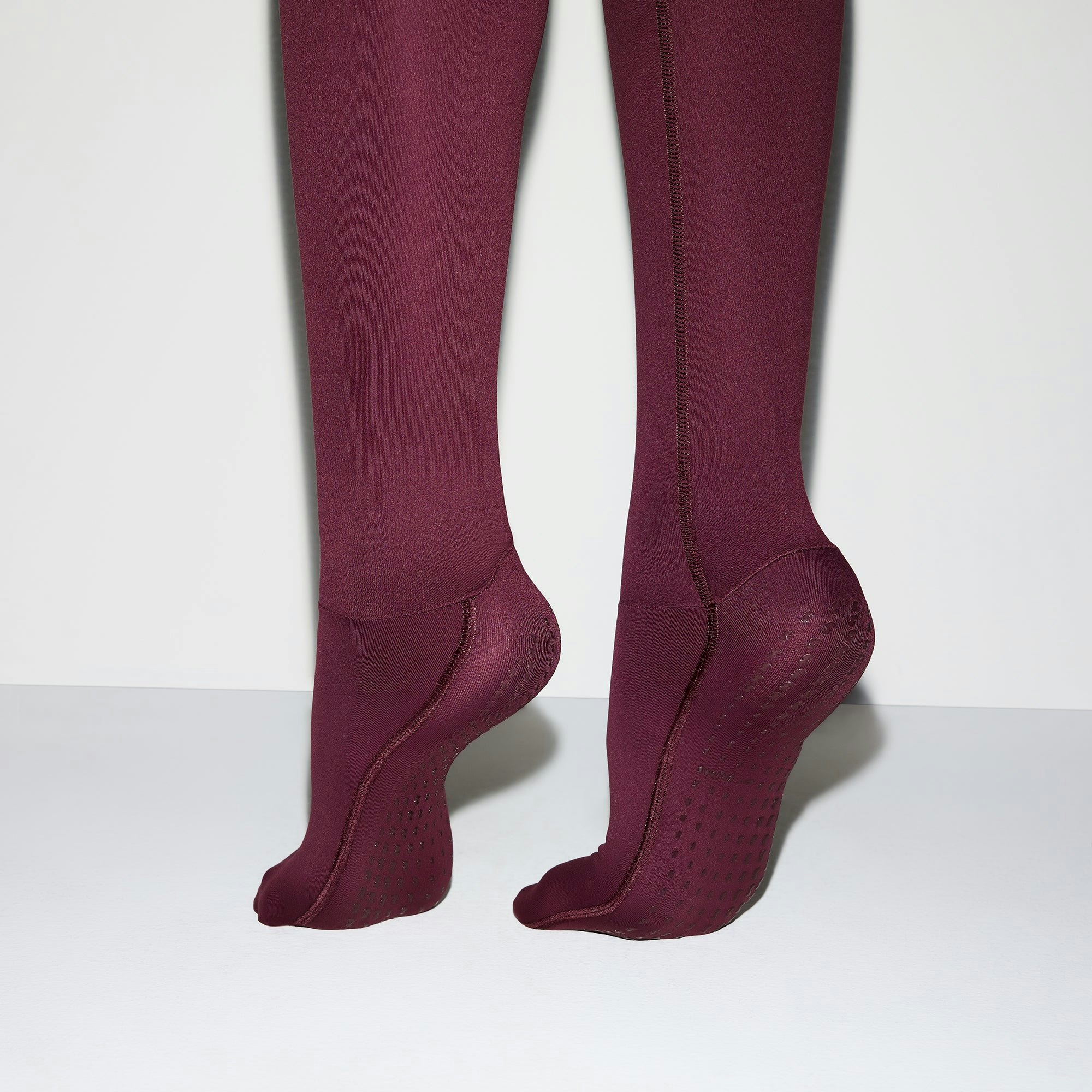 NikeSKIMS MATTE FOOTSIE GRIP LEGGING | CURRANT ON A MODEL BACK VIEW @ | FOCUS: 0.0, 1.0, 0.9