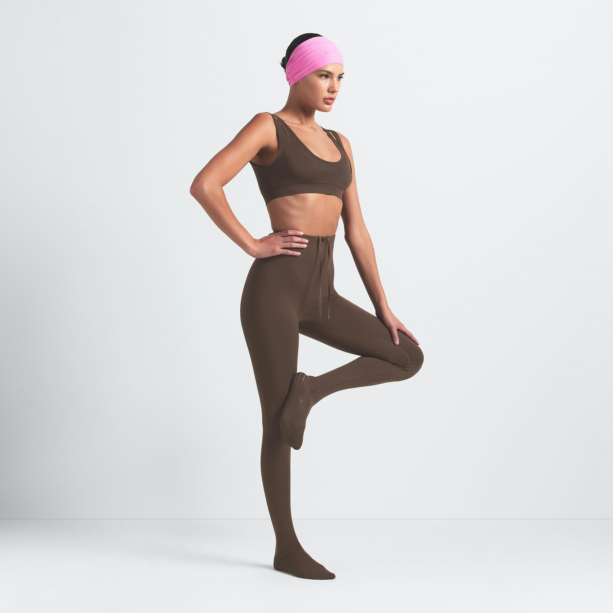 NikeSKIMS MATTE FOOTSIE GRIP LEGGING | DARK SEPIA ON A MODEL SIDE VIEW @ | FOCUS: 0.9, 0.1, 0.7