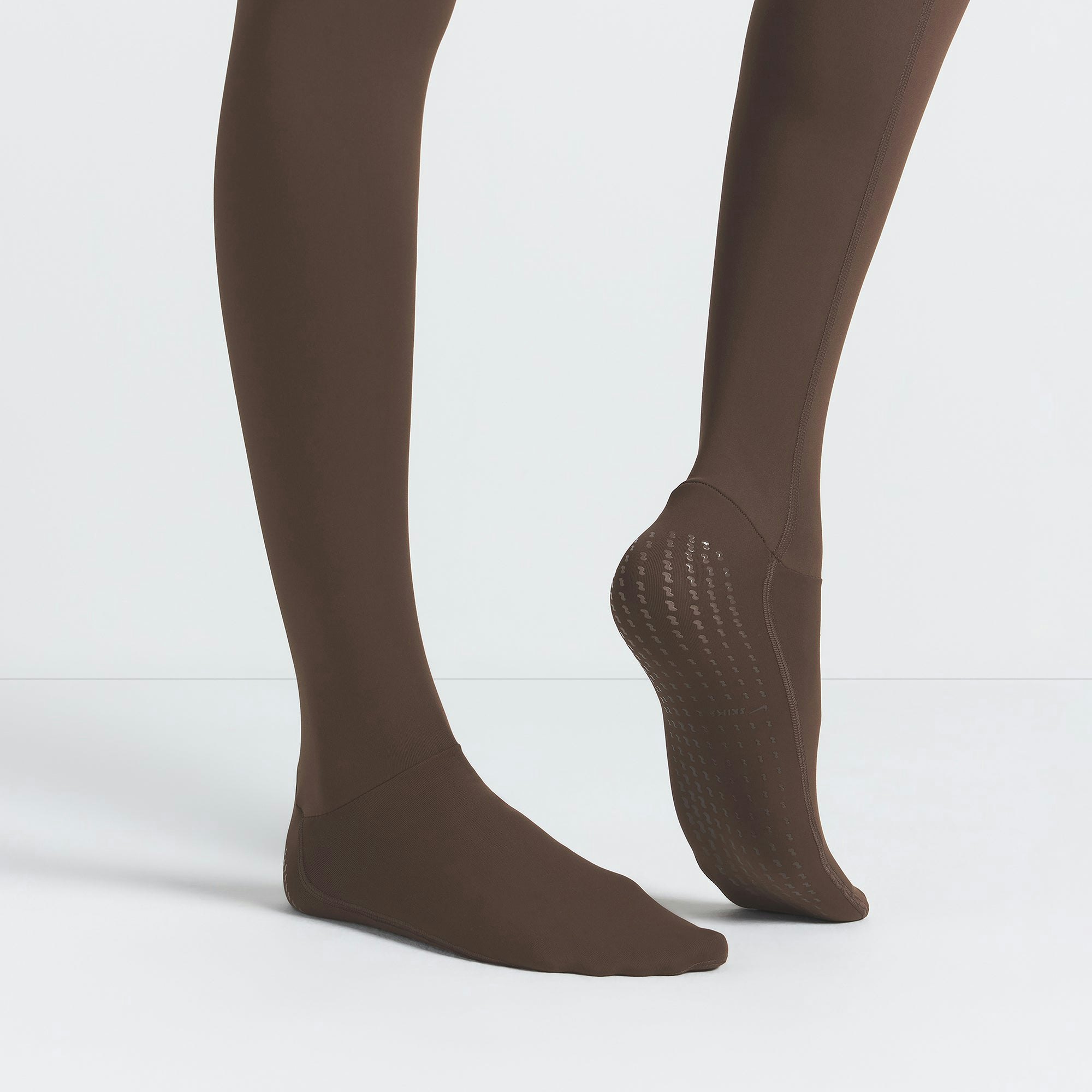 NikeSKIMS MATTE FOOTSIE GRIP LEGGING | DARK SEPIA ON A MODEL SIDE VIEW