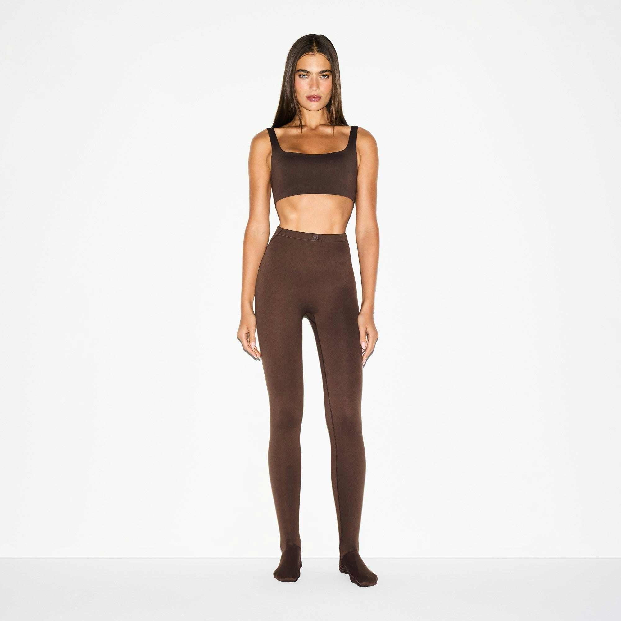 NikeSKIMS MATTE FOOTSIE GRIP LEGGING | DARK SEPIA ON A MODEL FRONT VIEW @ | FOCUS: 0.0, 1.0, 0.9