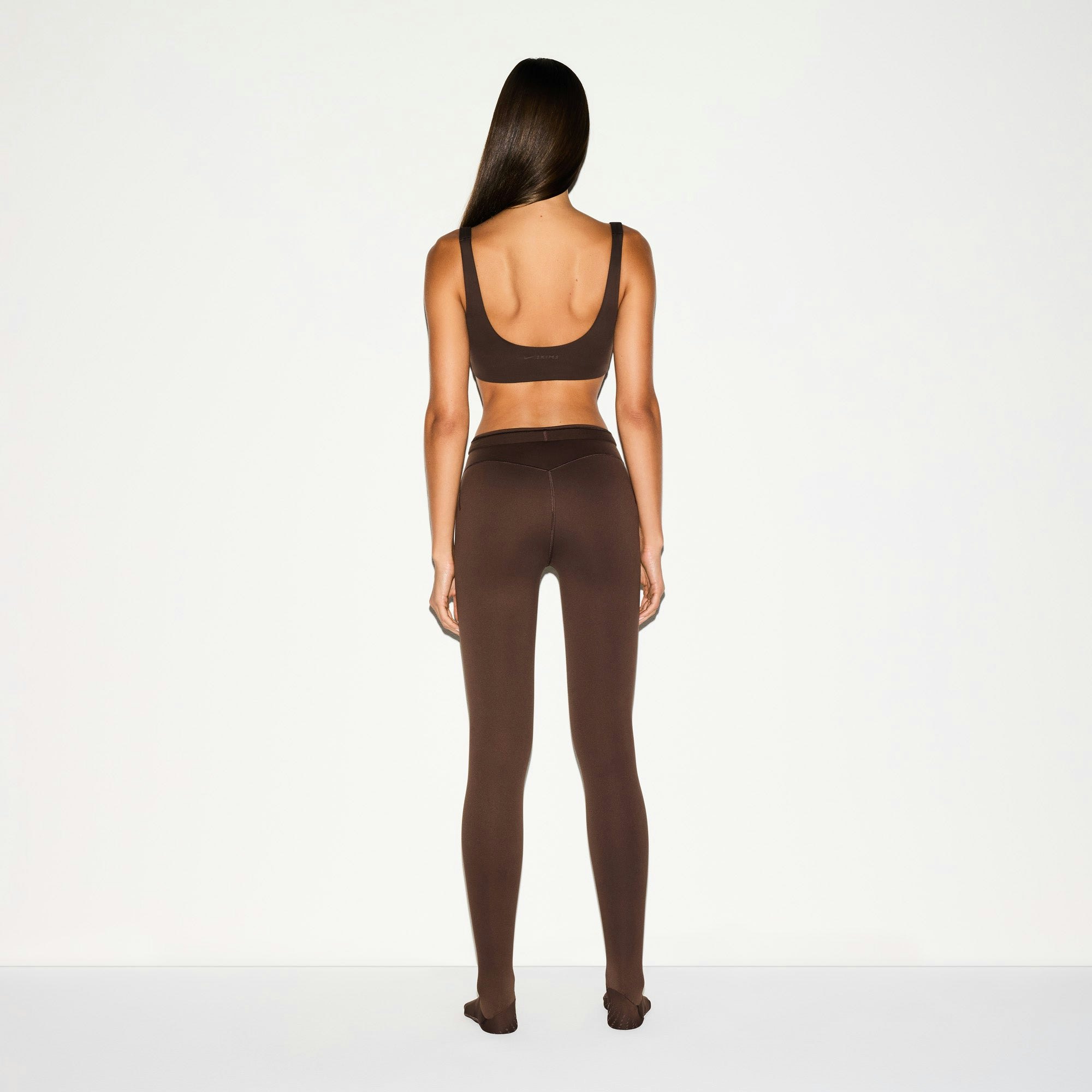 NikeSKIMS MATTE FOOTSIE GRIP LEGGING | DARK SEPIA ON A MODEL BACK VIEW @ | FOCUS: 0.0, 1.0, 0.9
