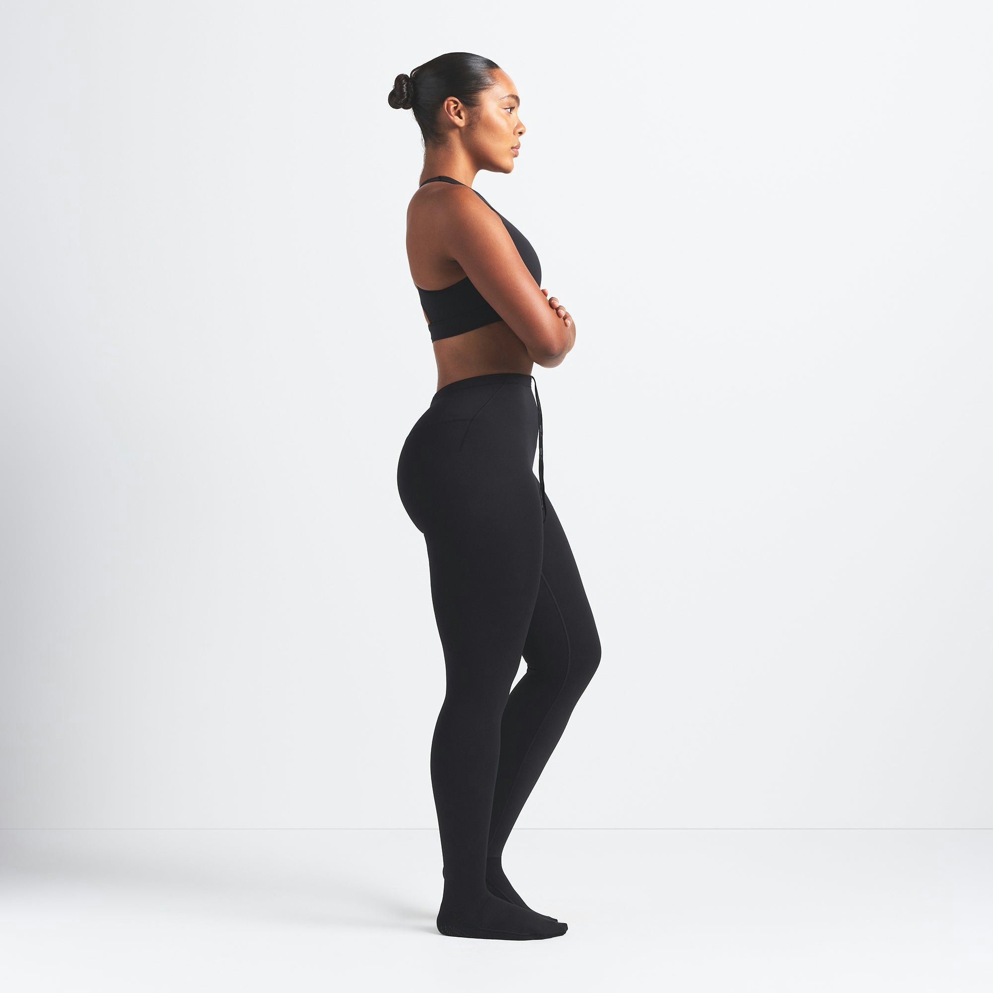 NikeSKIMS MATTE FOOTSIE GRIP LEGGING | OBSIDIAN ON A MODEL SIDE VIEW
