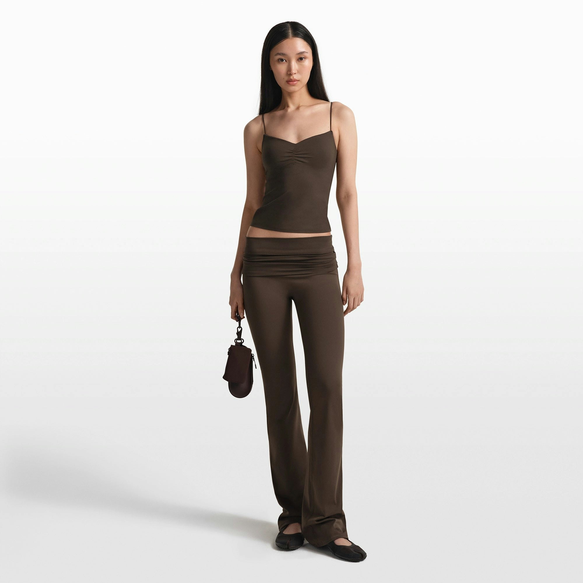 NikeSKIMS MATTE FOLDOVER SLIM FLARE LEGGING | DARK SEPIA ON A MODEL FRONT VIEW @ | FOCUS: 0.0, 1.0, 0.9