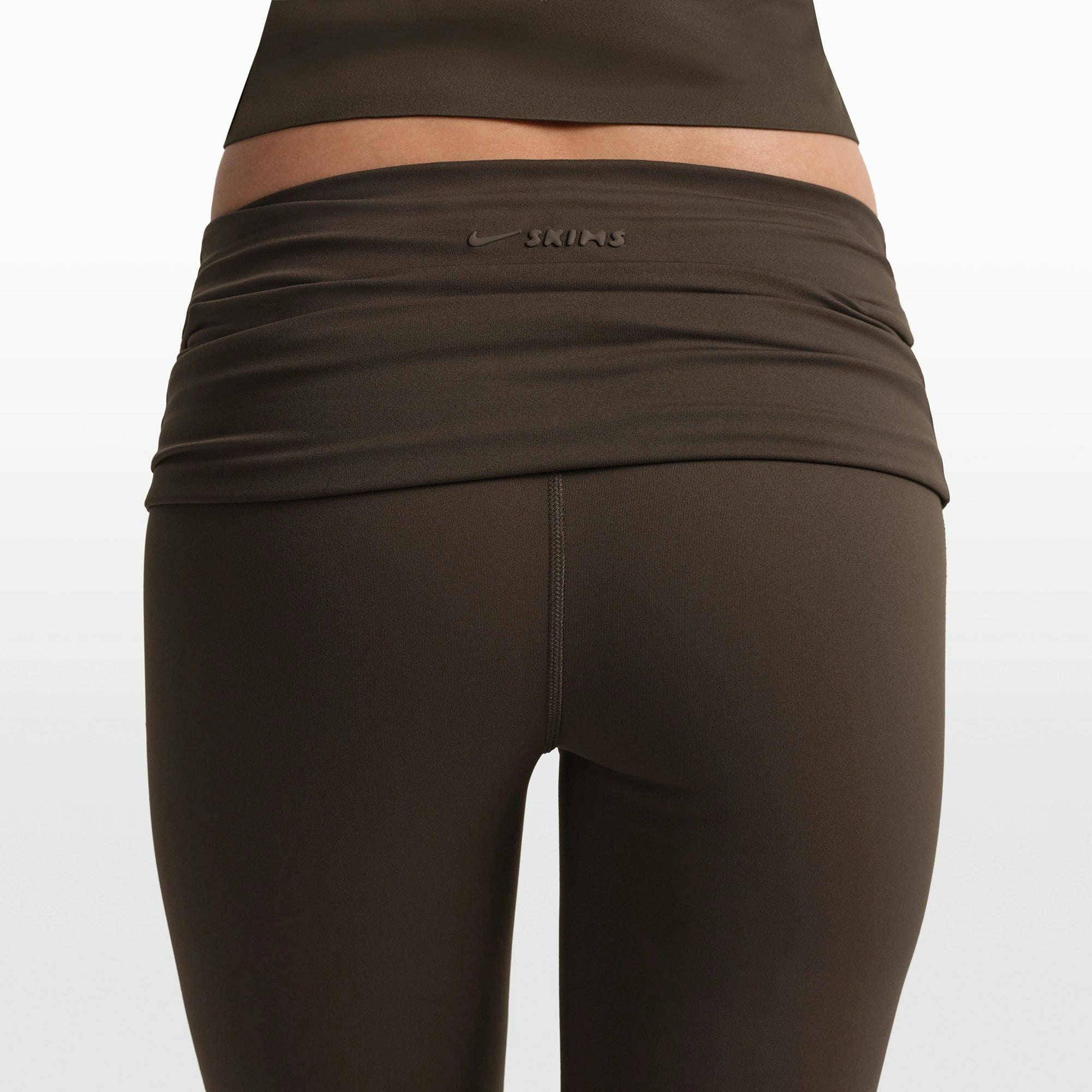 NikeSKIMS MATTE FOLDOVER SLIM FLARE LEGGING | DARK SEPIA ON A MODEL FRONT VIEW @ | FOCUS: 0.0, 1.0, 0.9