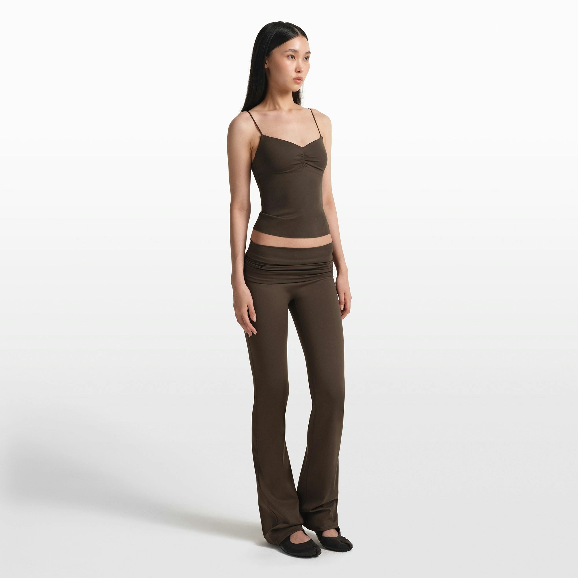 NikeSKIMS MATTE FOLDOVER SLIM FLARE LEGGING | DARK SEPIA ON A MODEL FRONT VIEW @ | FOCUS: 0.0, 1.0, 0.9