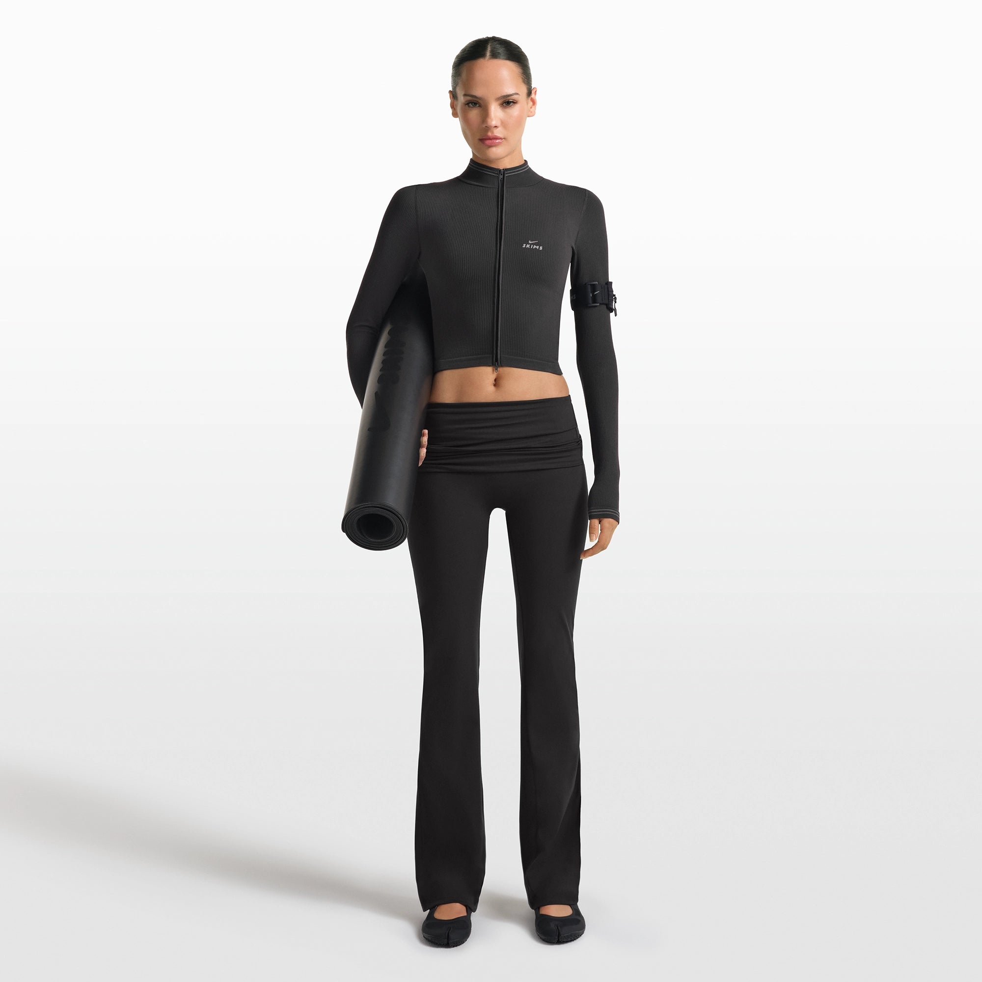 NikeSKIMS MATTE FOLDOVER SLIM FLARE LEGGING | OBSIDIAN ON A MODEL FRONT VIEW @ | FOCUS: 0.0, 1.0, 0.9