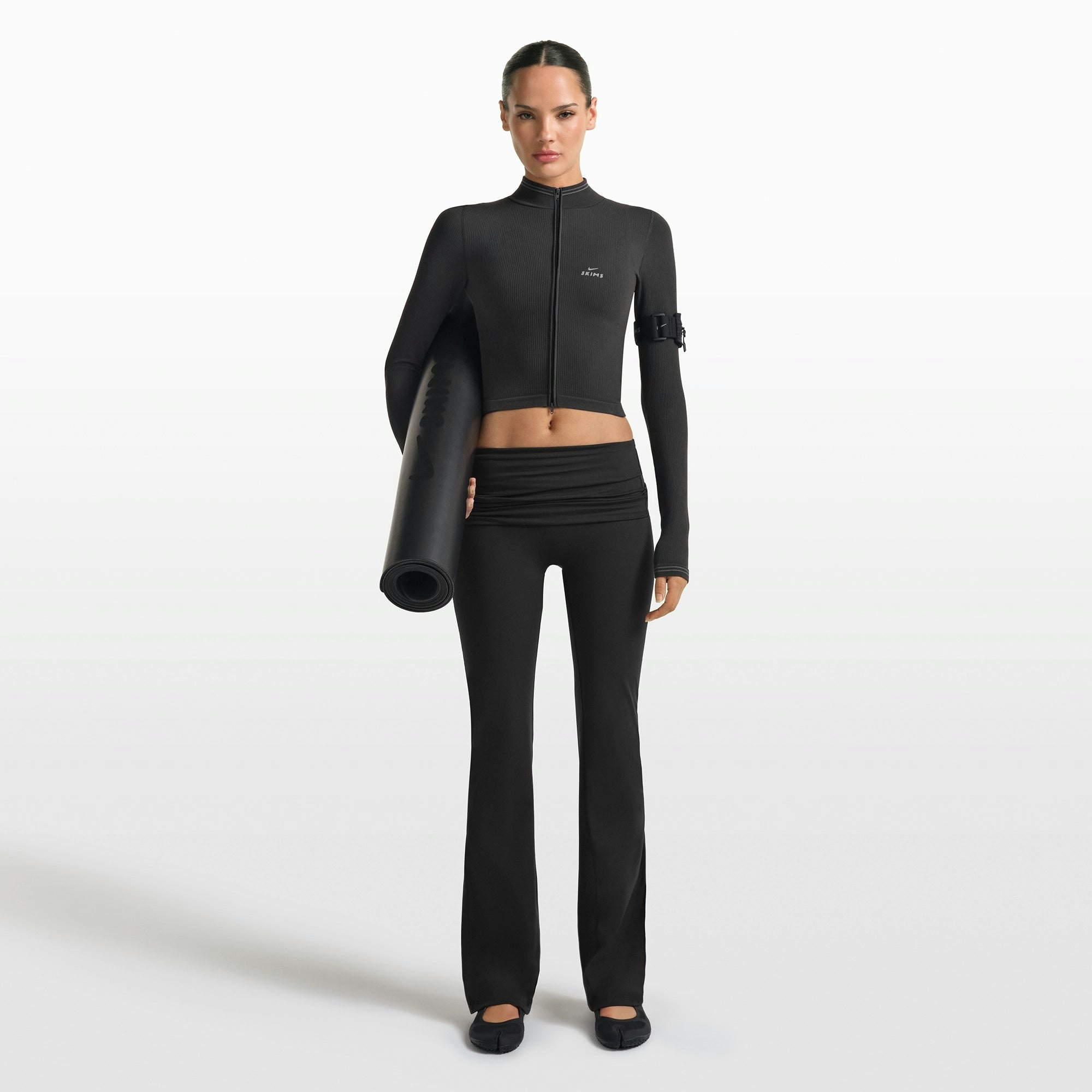 NikeSKIMS MATTE FOLDOVER SLIM FLARE LEGGING | OBSIDIAN ON A MODEL FRONT VIEW @ | FOCUS: 0.0, 1.0, 0.9