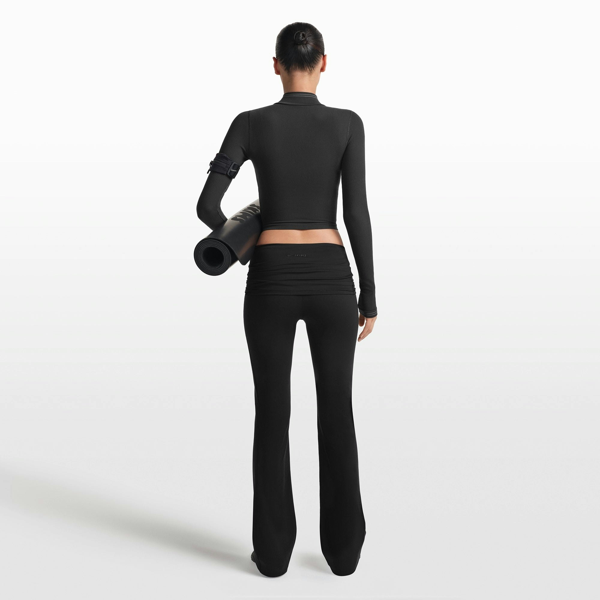 NikeSKIMS MATTE FOLDOVER SLIM FLARE LEGGING | OBSIDIAN ON A MODEL FRONT VIEW @ | FOCUS: 0.0, 1.0, 0.9