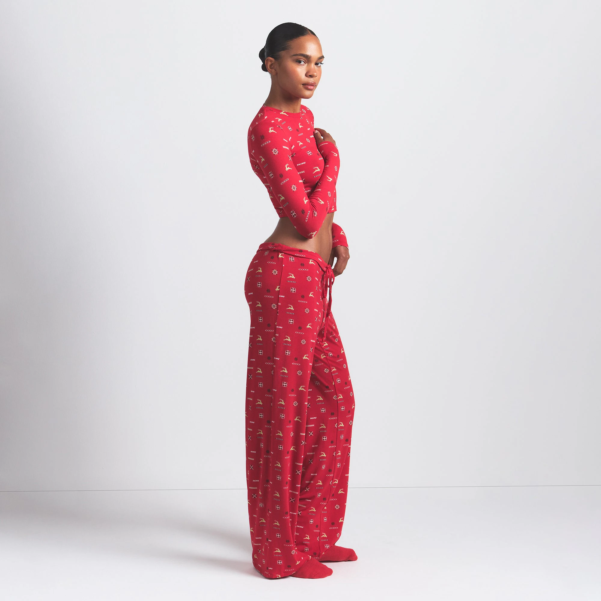 SKIMS SLEEP STRAIGHT LEG PANT | CRANBERRY VINTAGE DEER PRINT ON A MODEL SIDE VIEW @ | FOCUS: 0.0, 1.0, 0.9