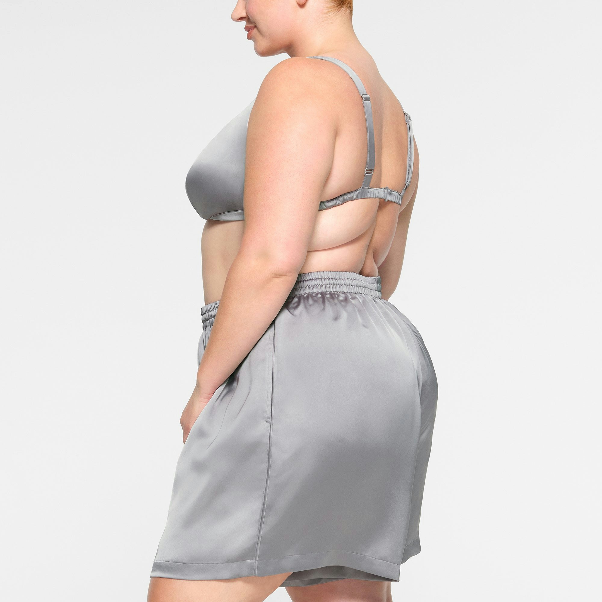SKIMS SPORTY SATIN LOOSE SHORT WORN BY A MODEL IN SIDE VIEW