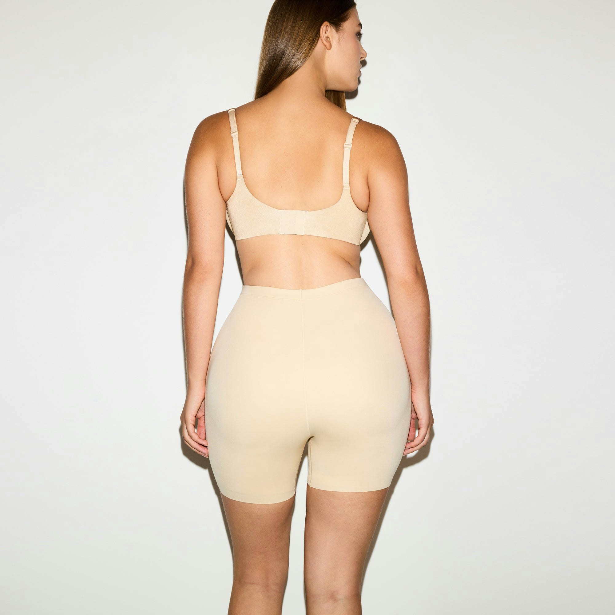 SKIMS BODY BUTT AND HIP ENHANCING MID THIGH SHORT | SAND ON A MODEL SIDE VIEW @ | FOCUS: 0.0, 1.0, 0.9