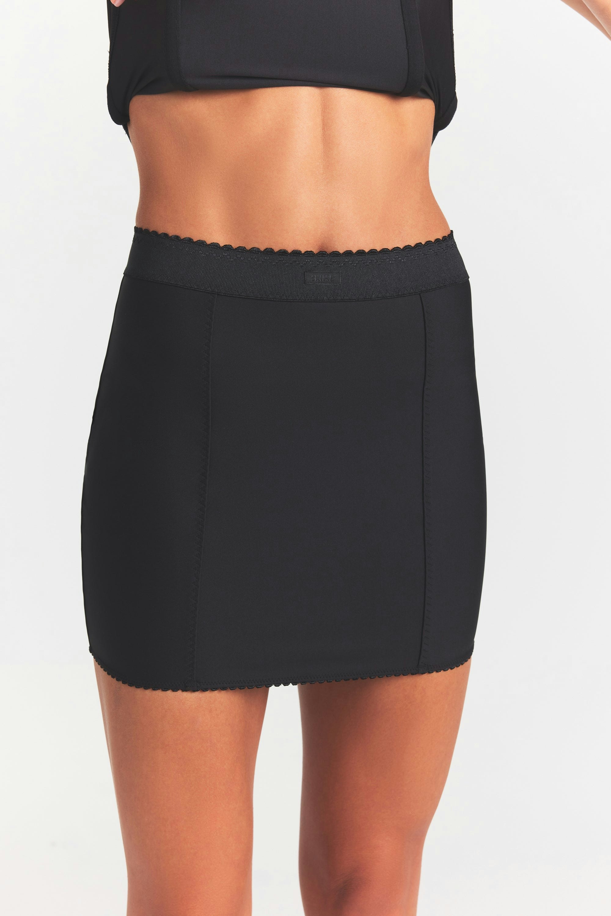 SKIMS BODY MINI GARTER SKIRT | ONYX ON A MODEL SIDE VIEW @ | FOCUS: 0.0, 1.0, 0.9