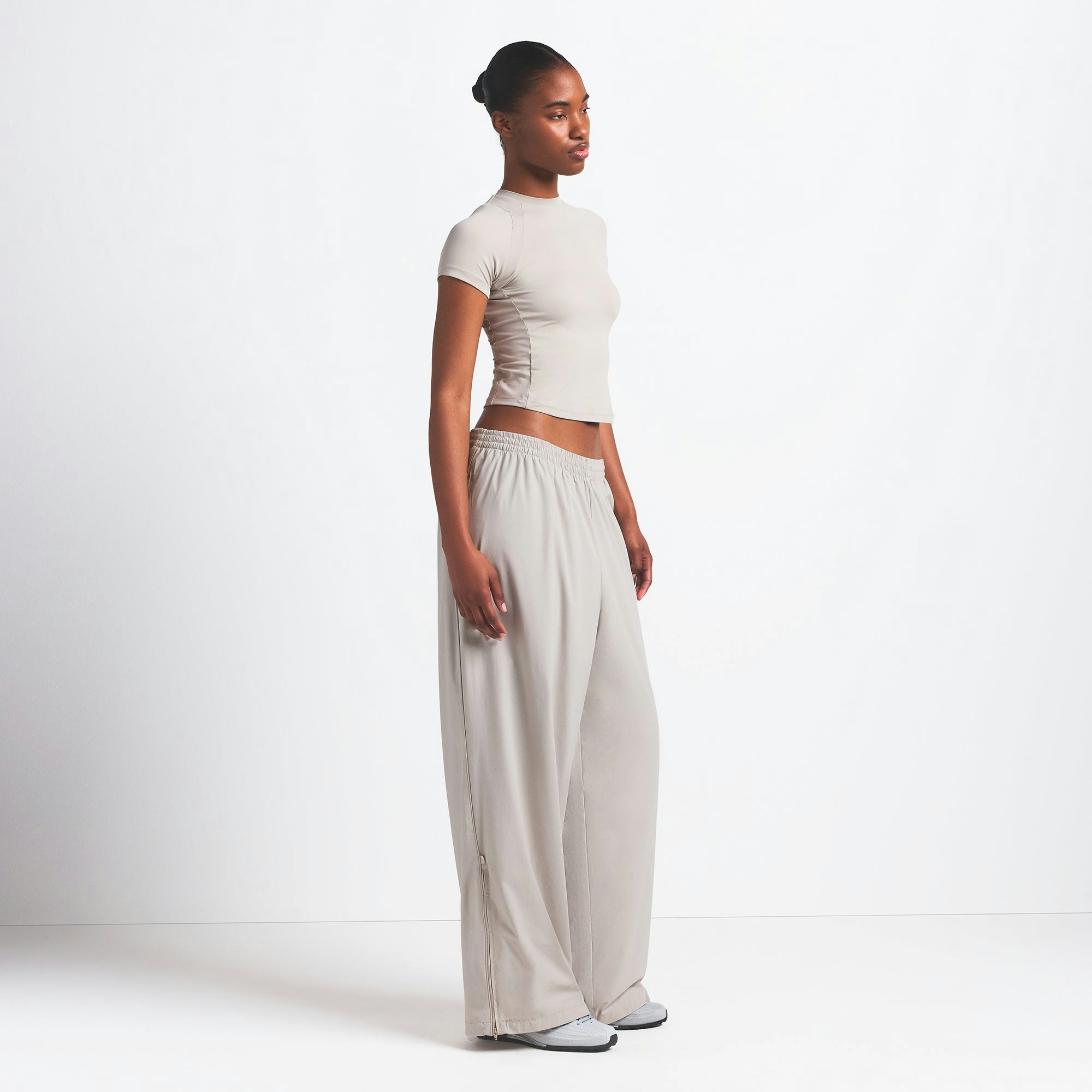 NikeSKIMS WOVEN NYLON OVERSIZED TRACK PANT | STONE ON A MODEL SIDE VIEW @ | FOCUS: 0.0, 1.0, 0.9