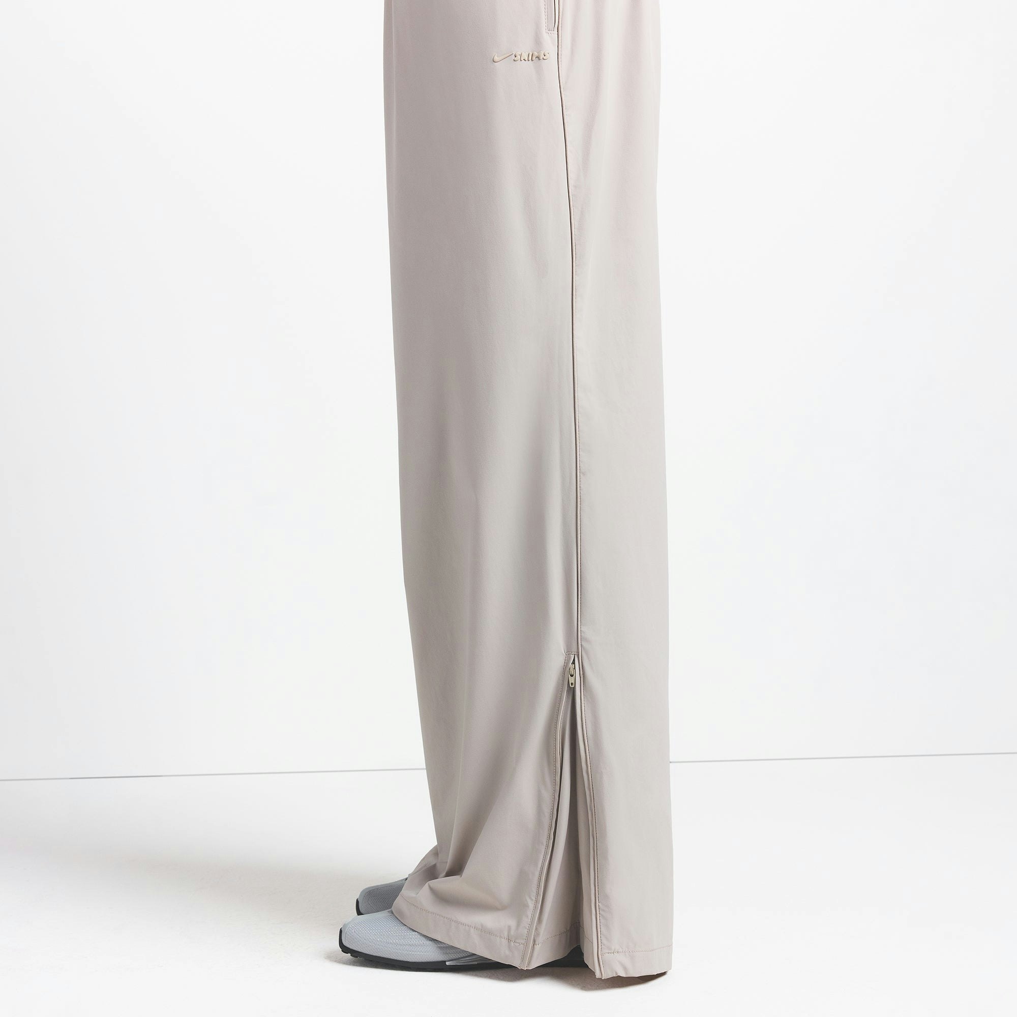 NikeSKIMS WOVEN NYLON OVERSIZED TRACK PANT | STONE ON A MODEL SIDE VIEW @ | FOCUS: 0.0, 1.0, 0.9