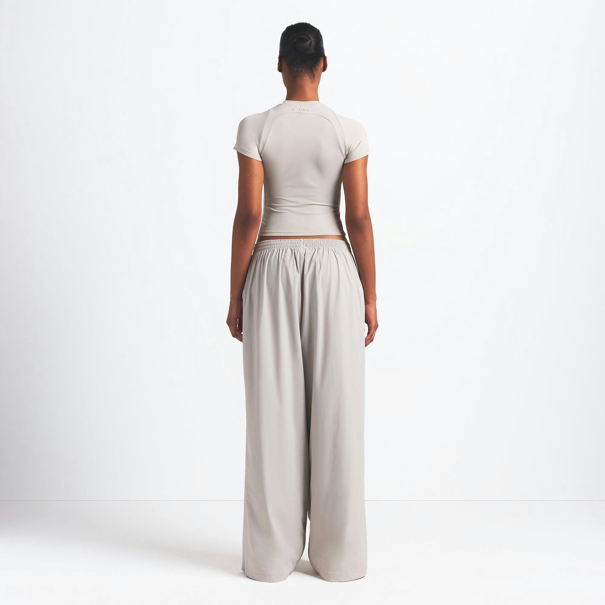 NikeSKIMS WOVEN NYLON OVERSIZED TRACK PANT | STONE ON A MODEL BACK VIEW @ | FOCUS: 0.0, 1.0, 0.9