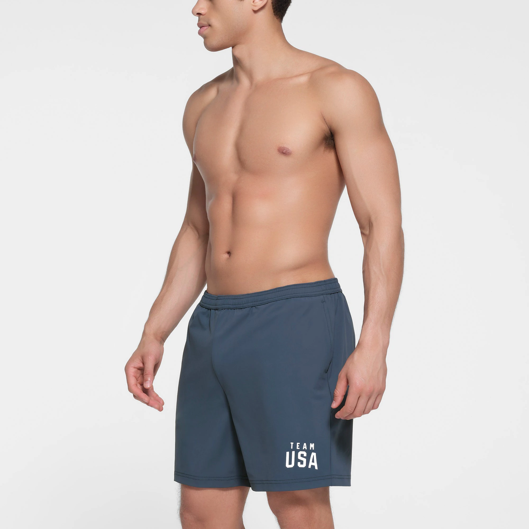 SKIMS FOR TEAM USA MENS OLYMPIC SWIM TRUNK | NAVY ON A MODEL SIDE VIEW